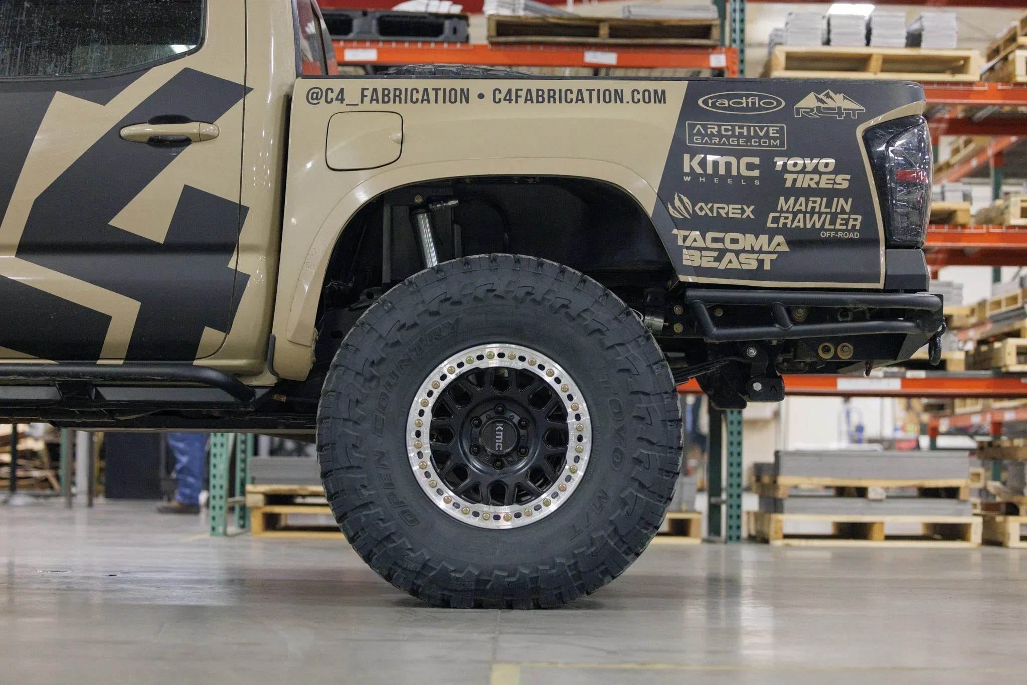 Toyota Tacoma with off-road KMC wheels, Toyo Open Country tire, overlanding decals in garage