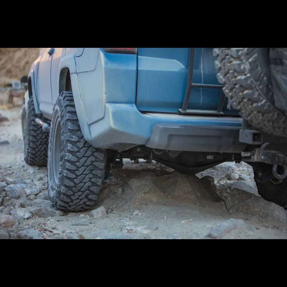 Off-road vehicle with rugged tires on rocky terrain, ideal for overlanding and adventure camping