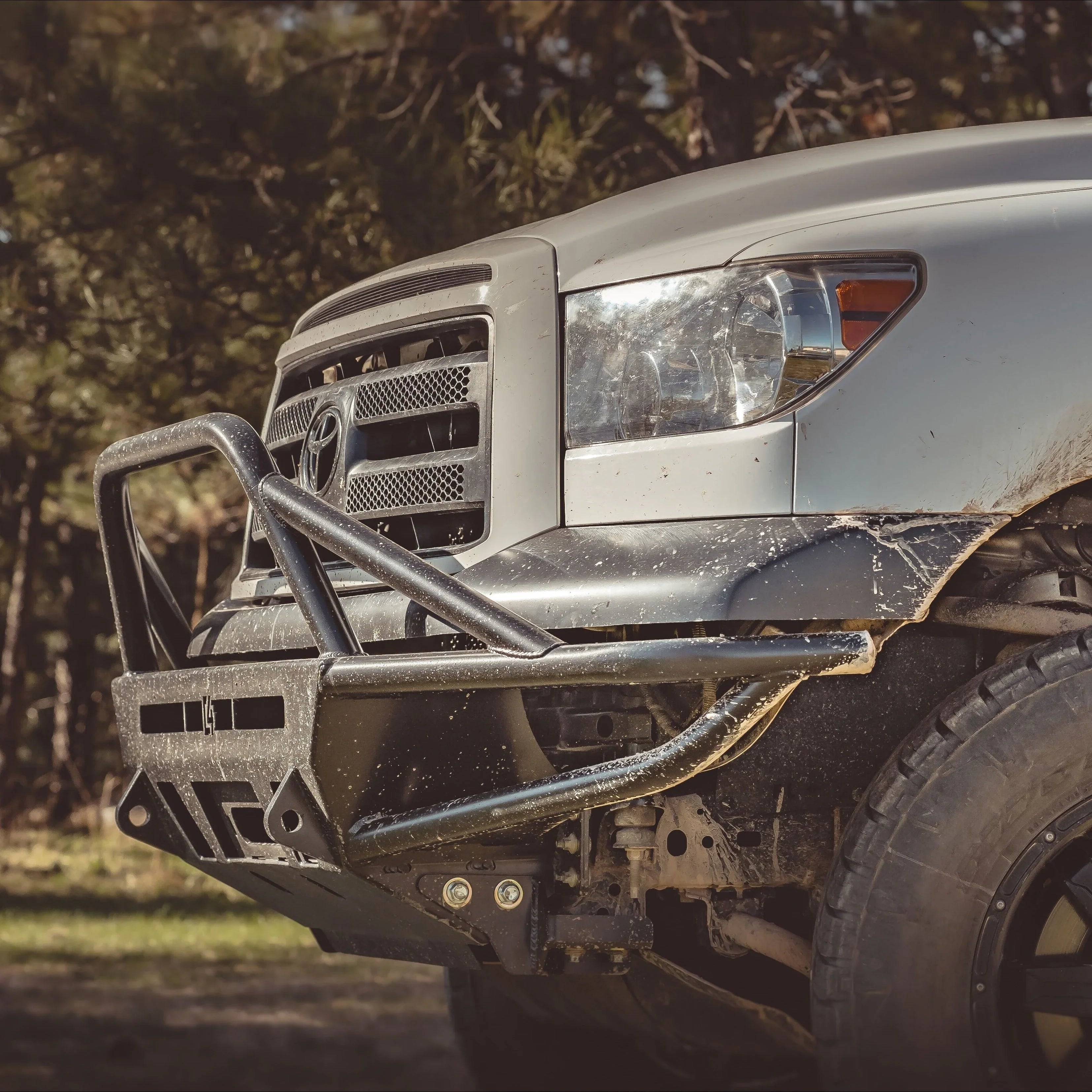 Toyota Tundra with heavy-duty off-road front bumper in a forest setting