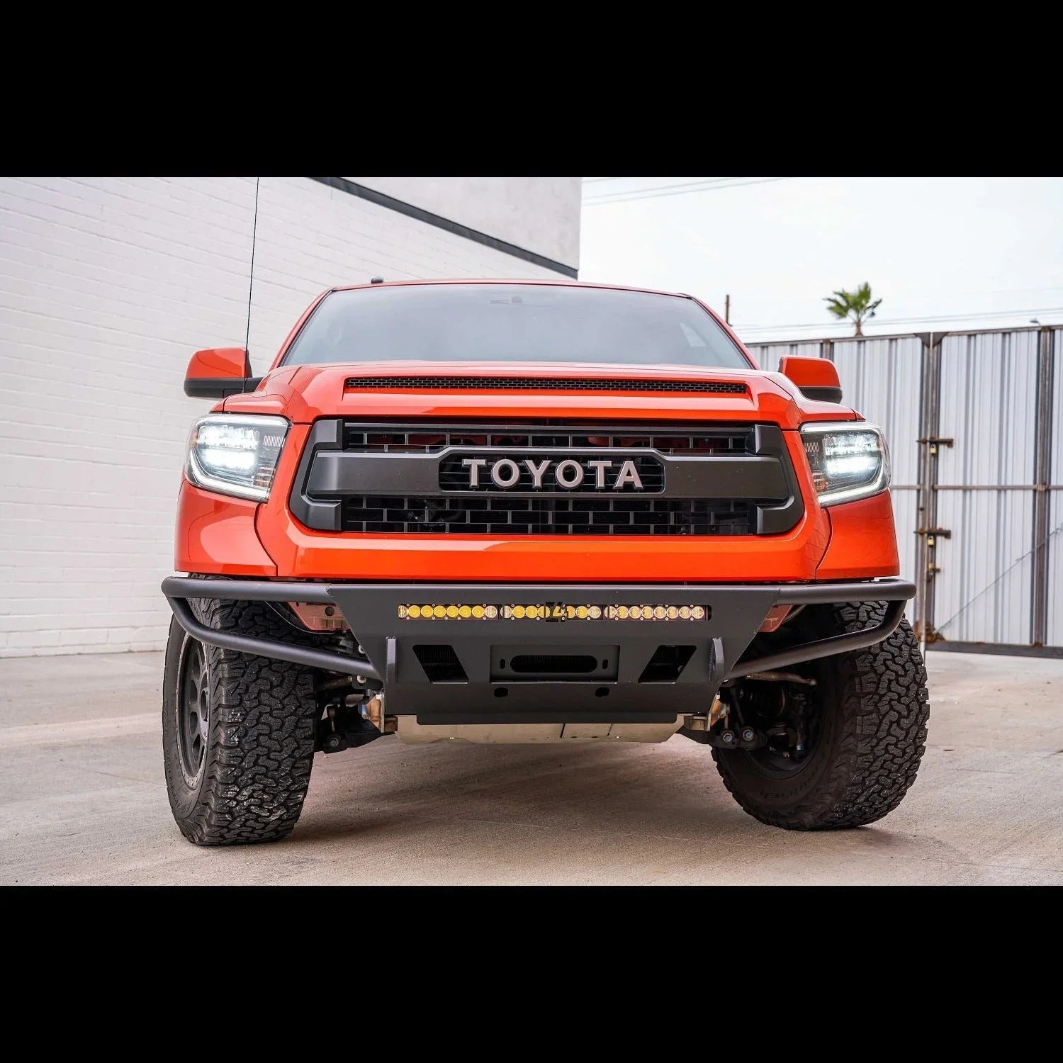 Orange Toyota Tundra with off-road steel front bumper and LED light bar, front view