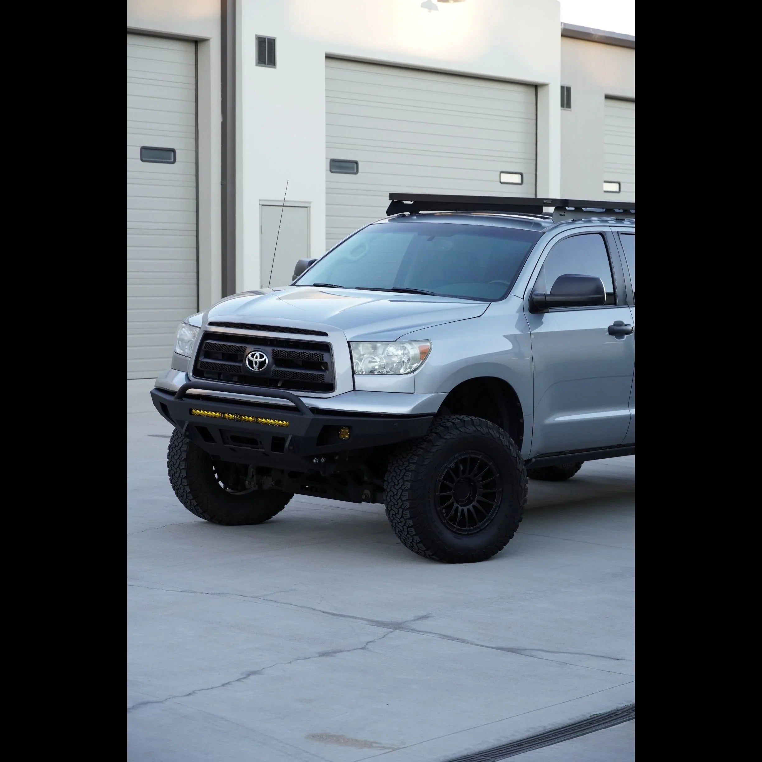 Lifted Toyota Tundra with off-road front bumper and roof rack in parking lot