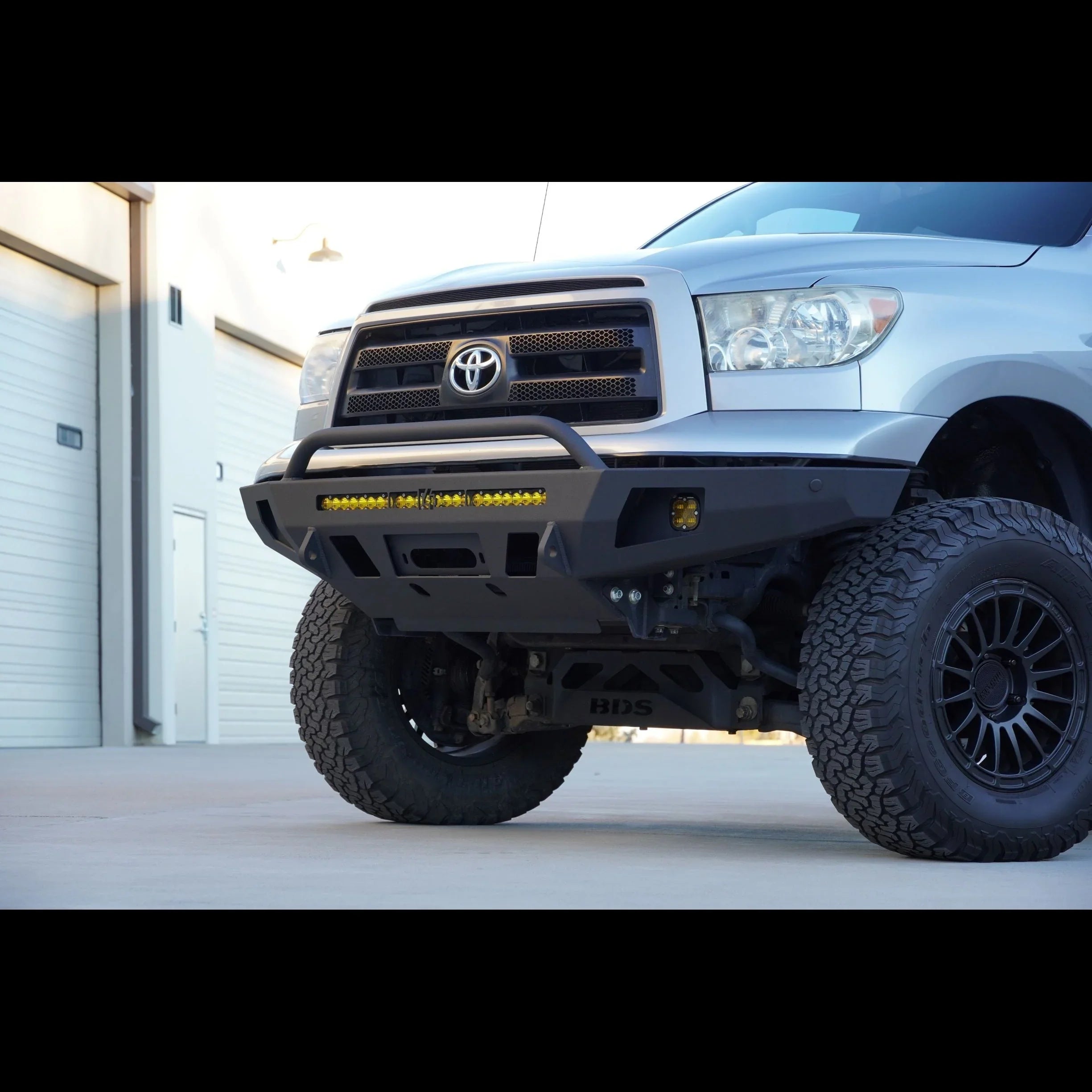 Toyota Tundra with off-road front bumper, aftermarket wheels, and yellow LED light bar