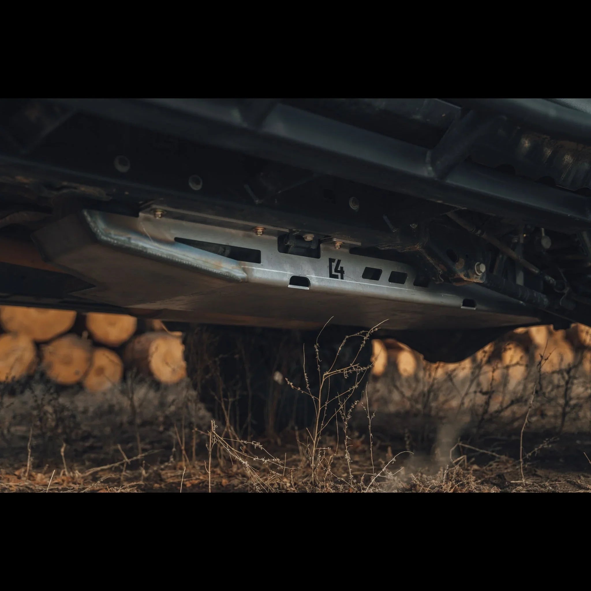 Heavy-duty aluminum skid plate mounted under off-road vehicle in outdoor setting
