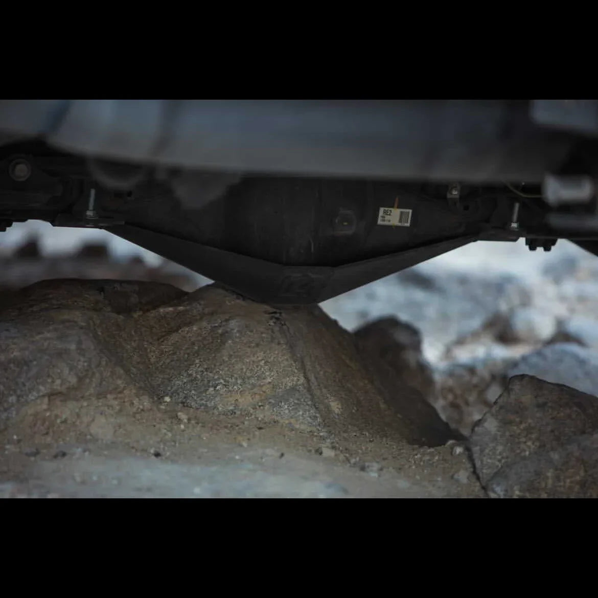 Vehicle skid plate protecting undercarriage on rocky off-road terrain