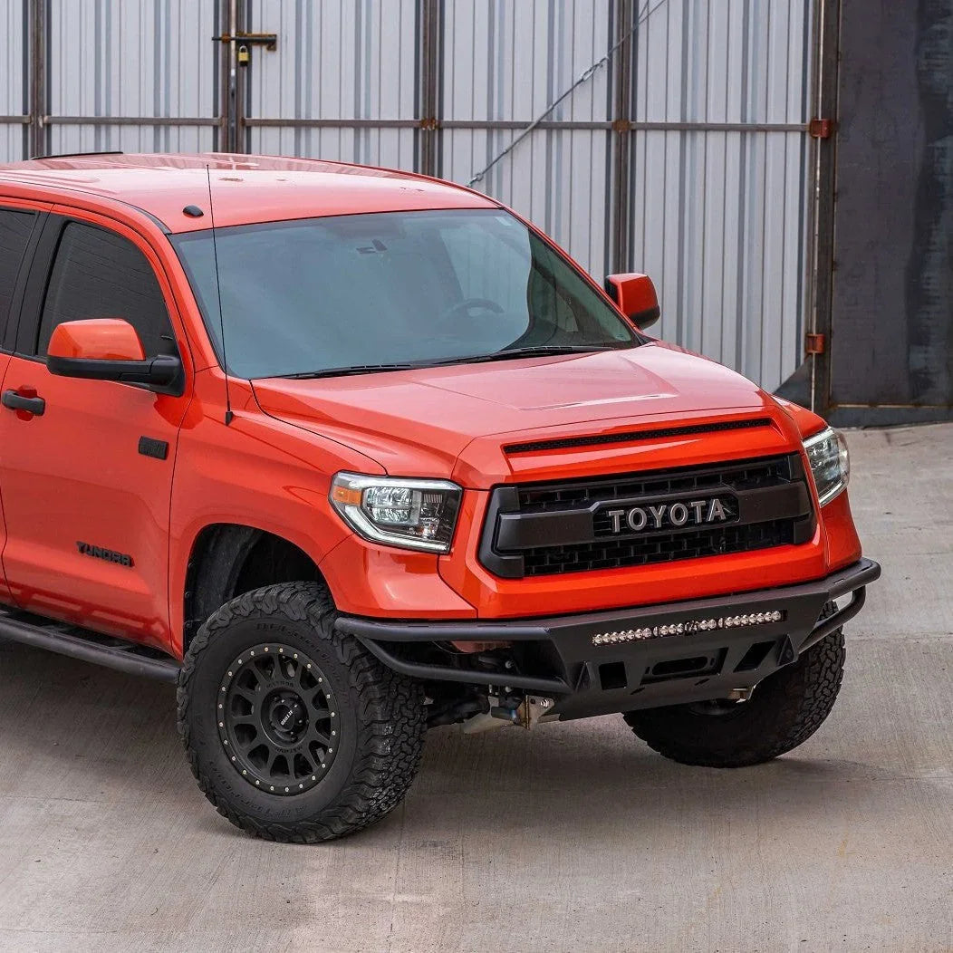 Orange Toyota Tundra truck with off-road bumper and rugged tires parked outdoors