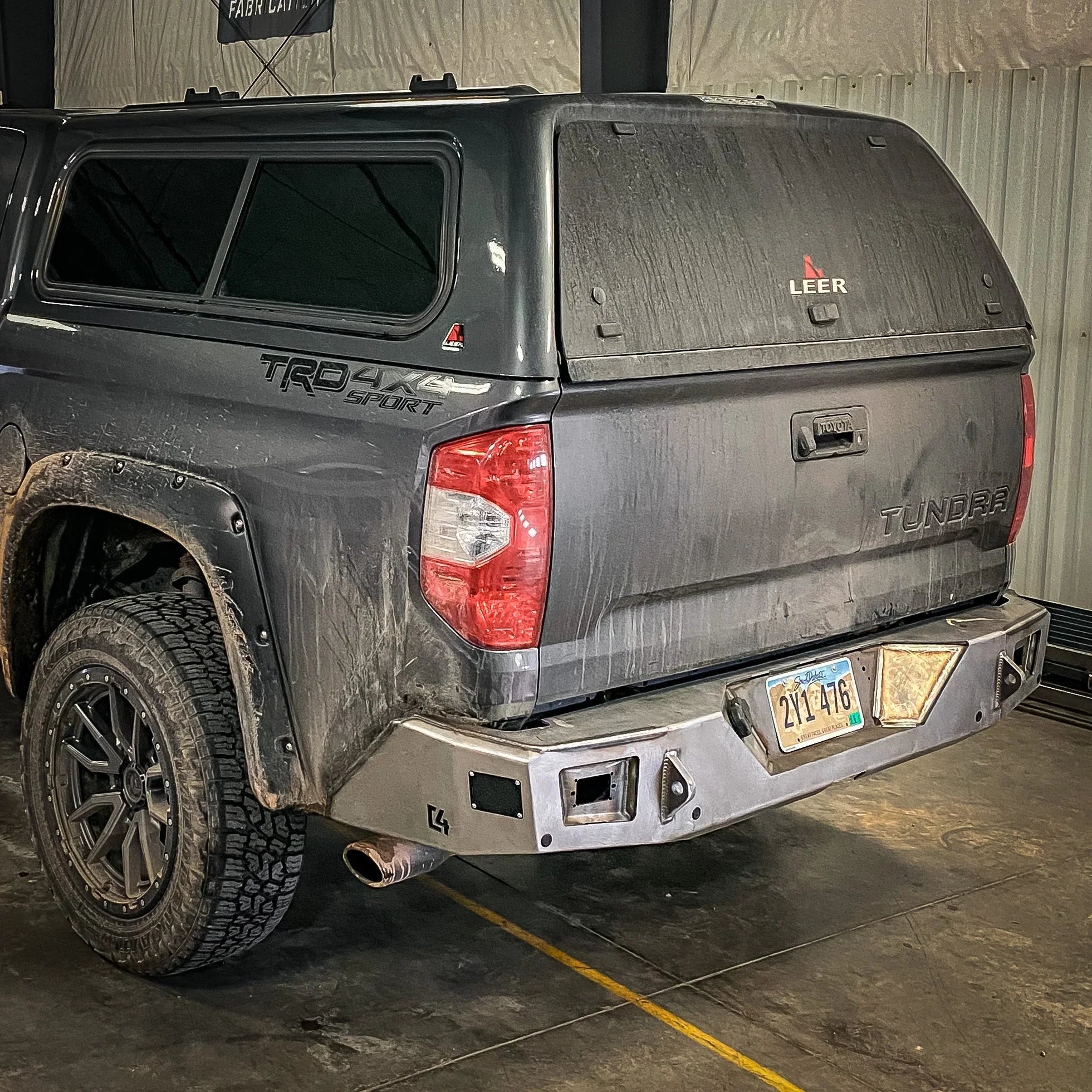 Toyota Tundra TRD 4x4 Sport with Leer camper shell and aftermarket steel rear bumper in garage