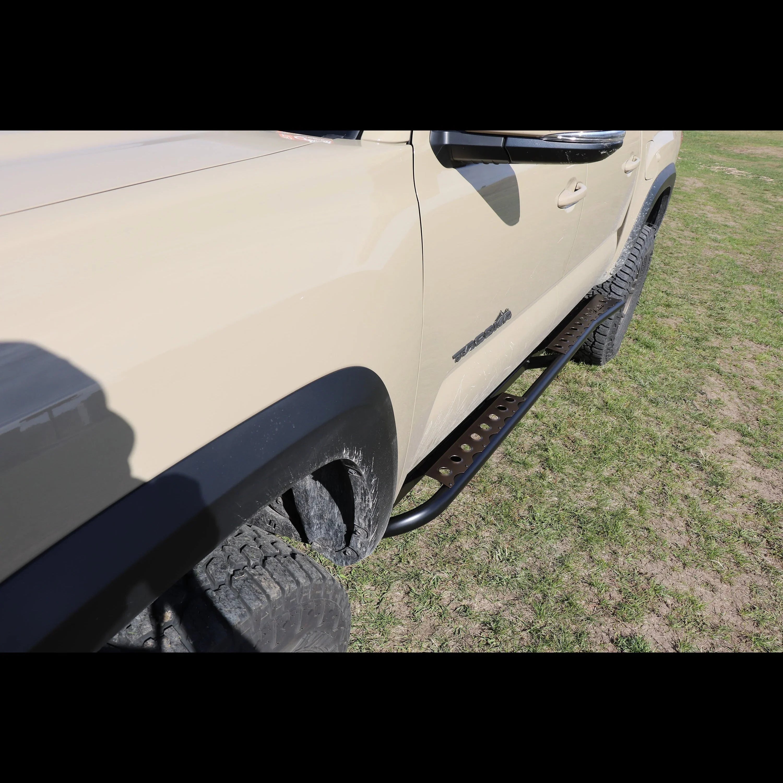 Toyota Tacoma with black off-road rock sliders side step on grass
