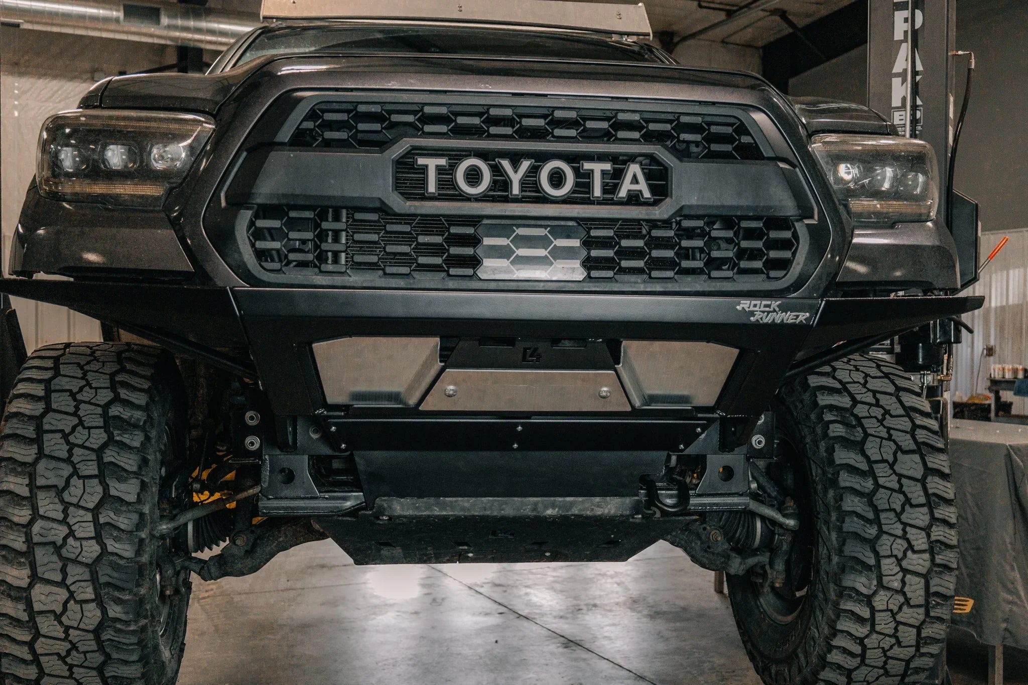 Toyota Tacoma with off-road Rock Runner front bumper and skid plate in a garage