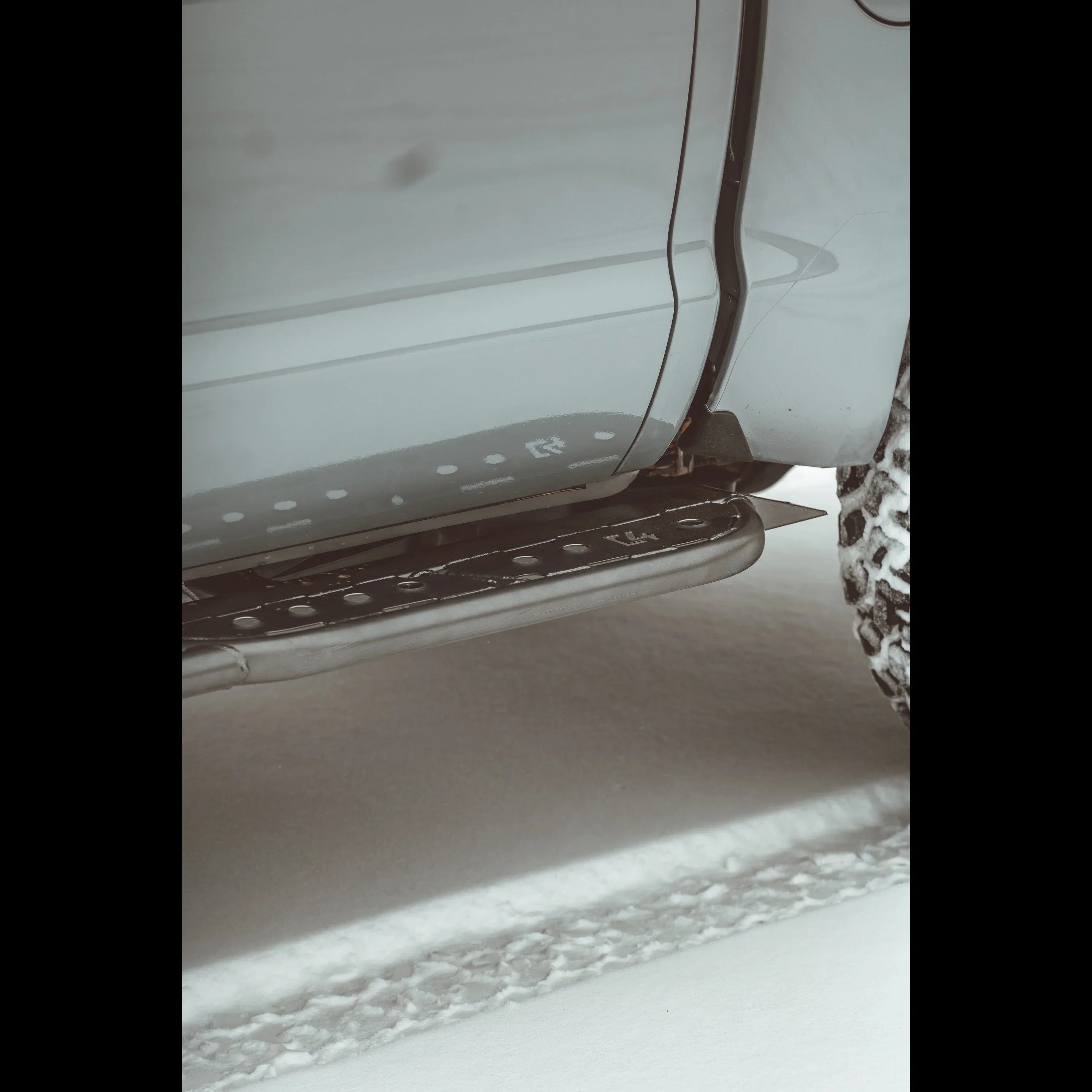 Off-road truck with rugged side step and snow tires on snowy terrain