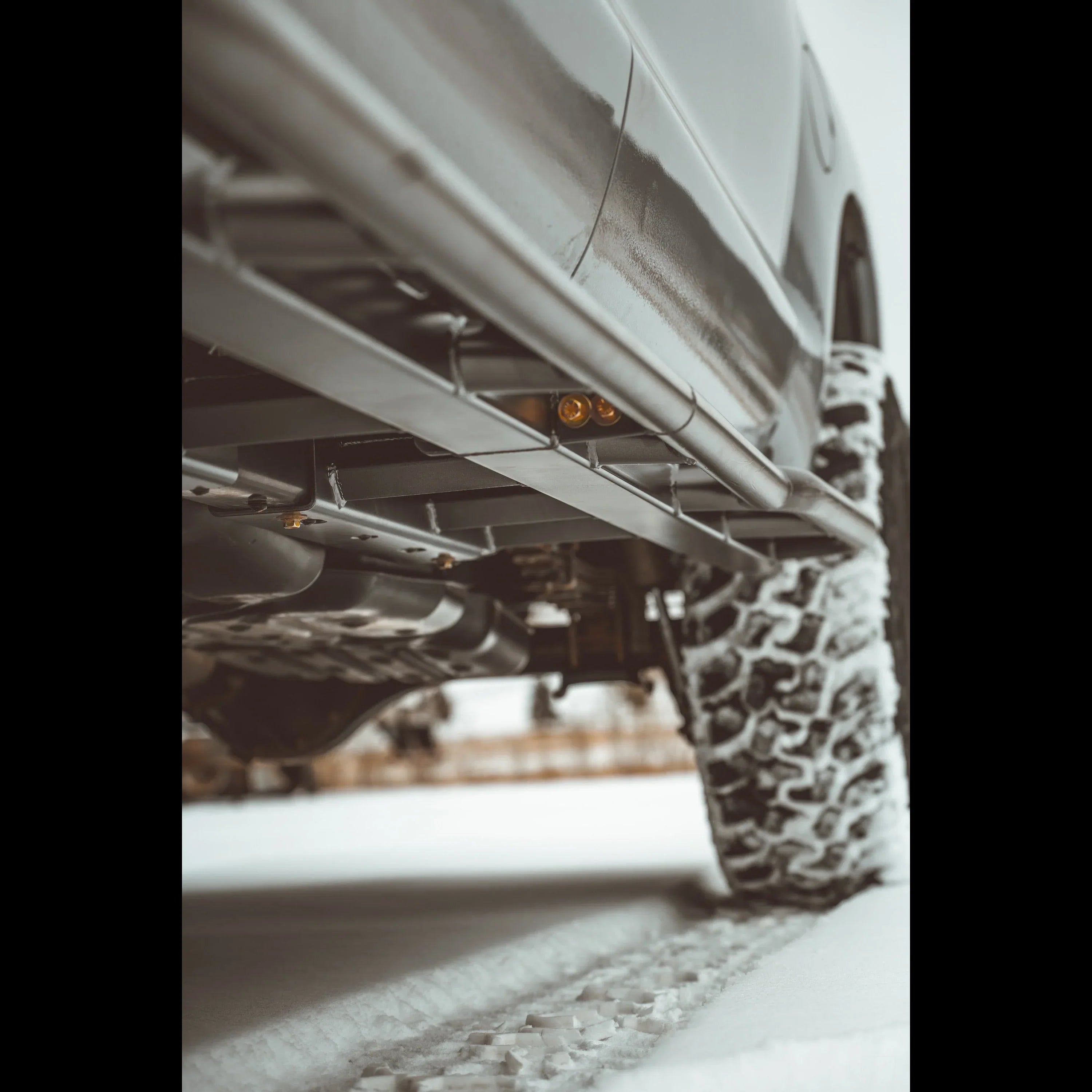 Off-road vehicle with rock sliders and all-terrain tires driving on snow