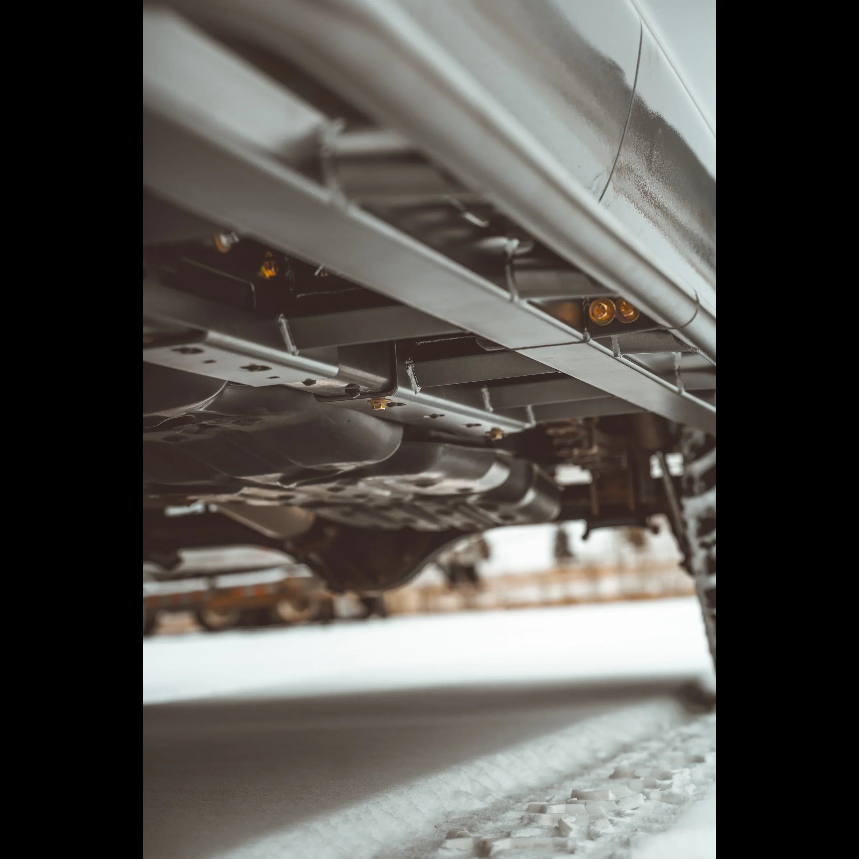 Close-up of off-road vehicle rock sliders and undercarriage protection on snow