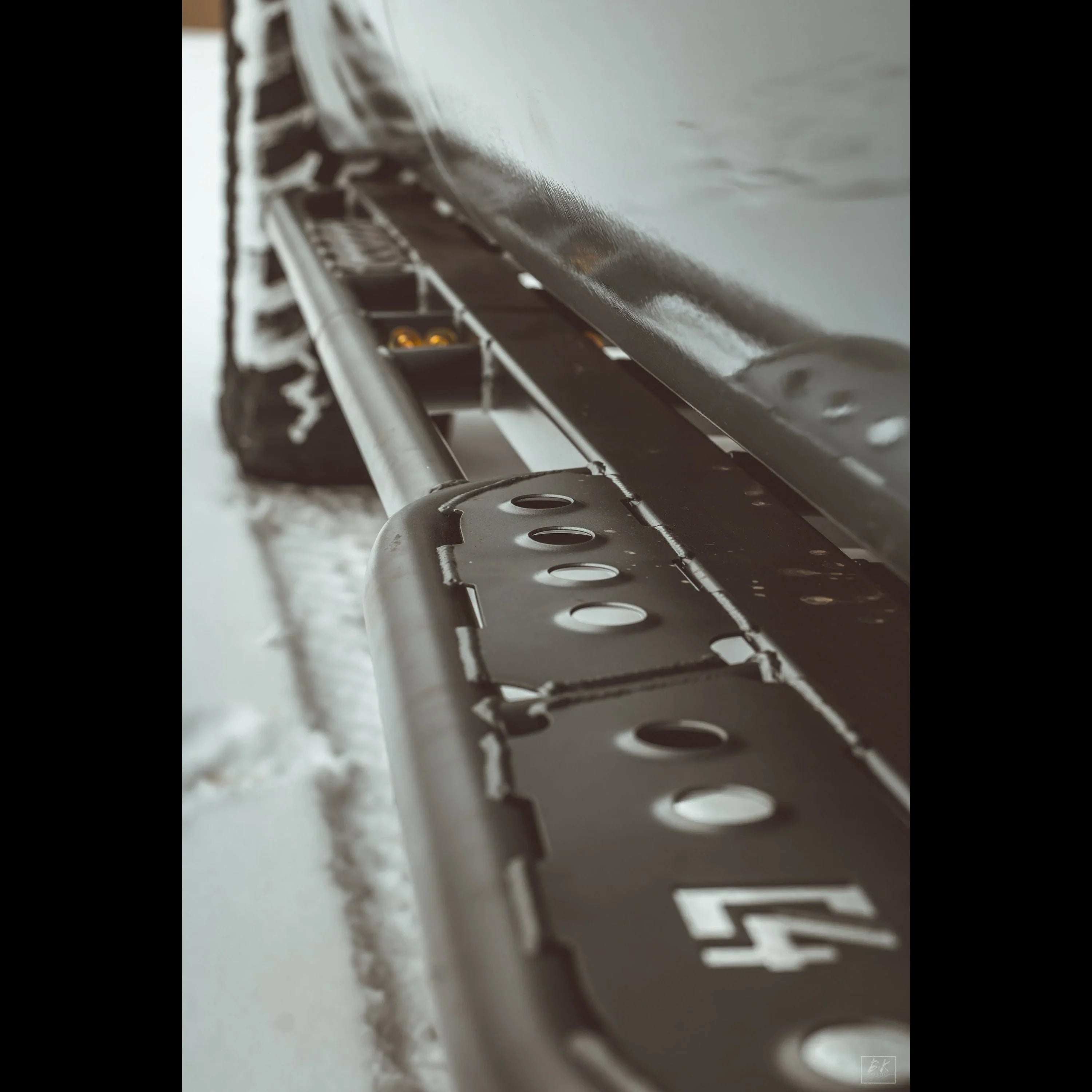 Heavy-duty black metal rock slider on vehicle side, snow in background, off-road accessory