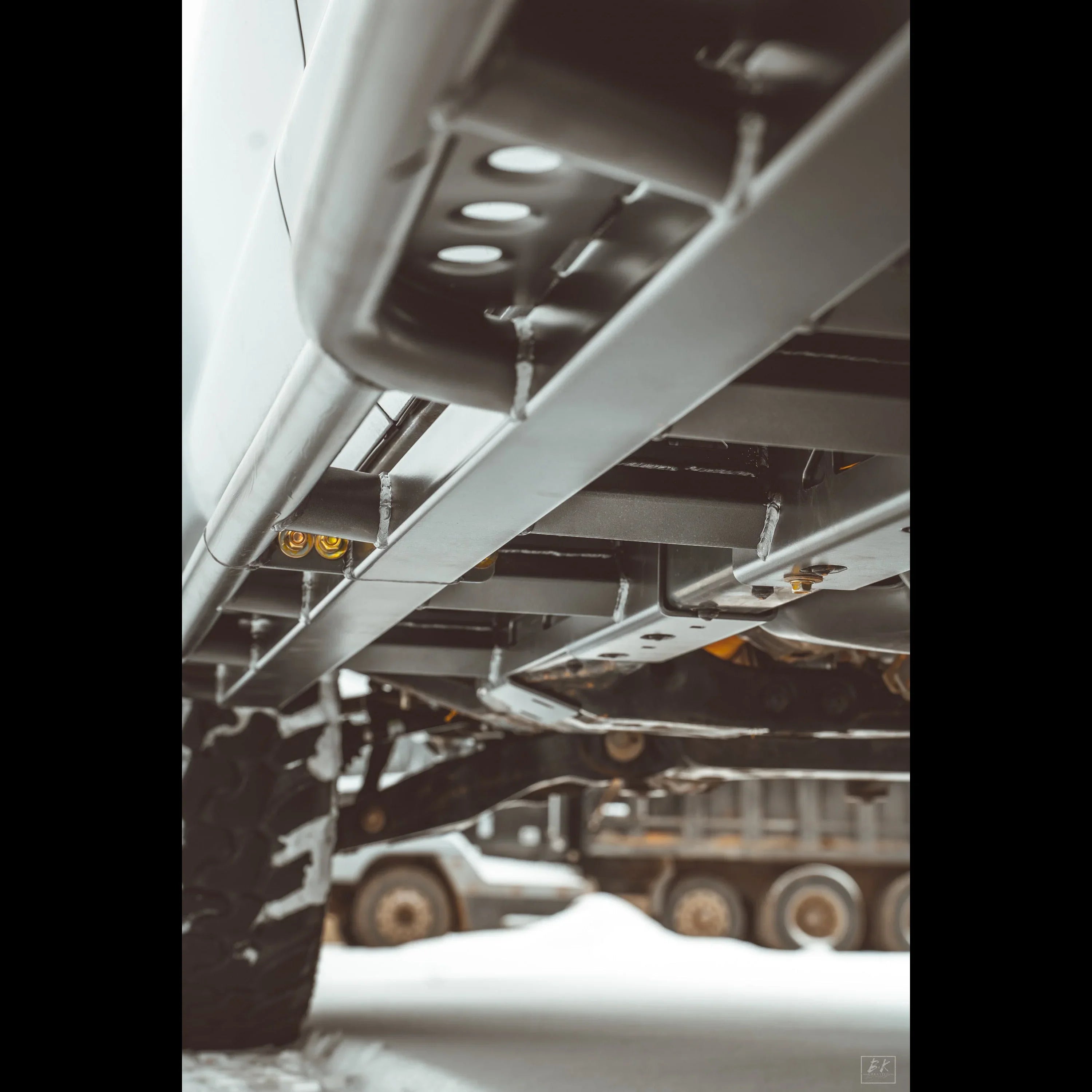 Close-up of off-road truck rock sliders and undercarriage on snowy ground