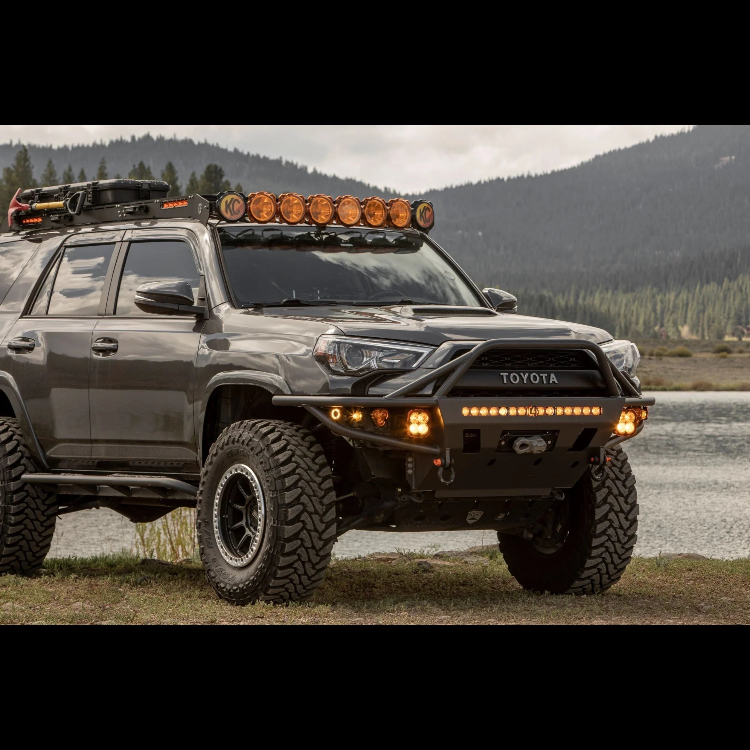 Lifted Toyota 4Runner with off-road accessories, roof lights, and rugged tires by a lake