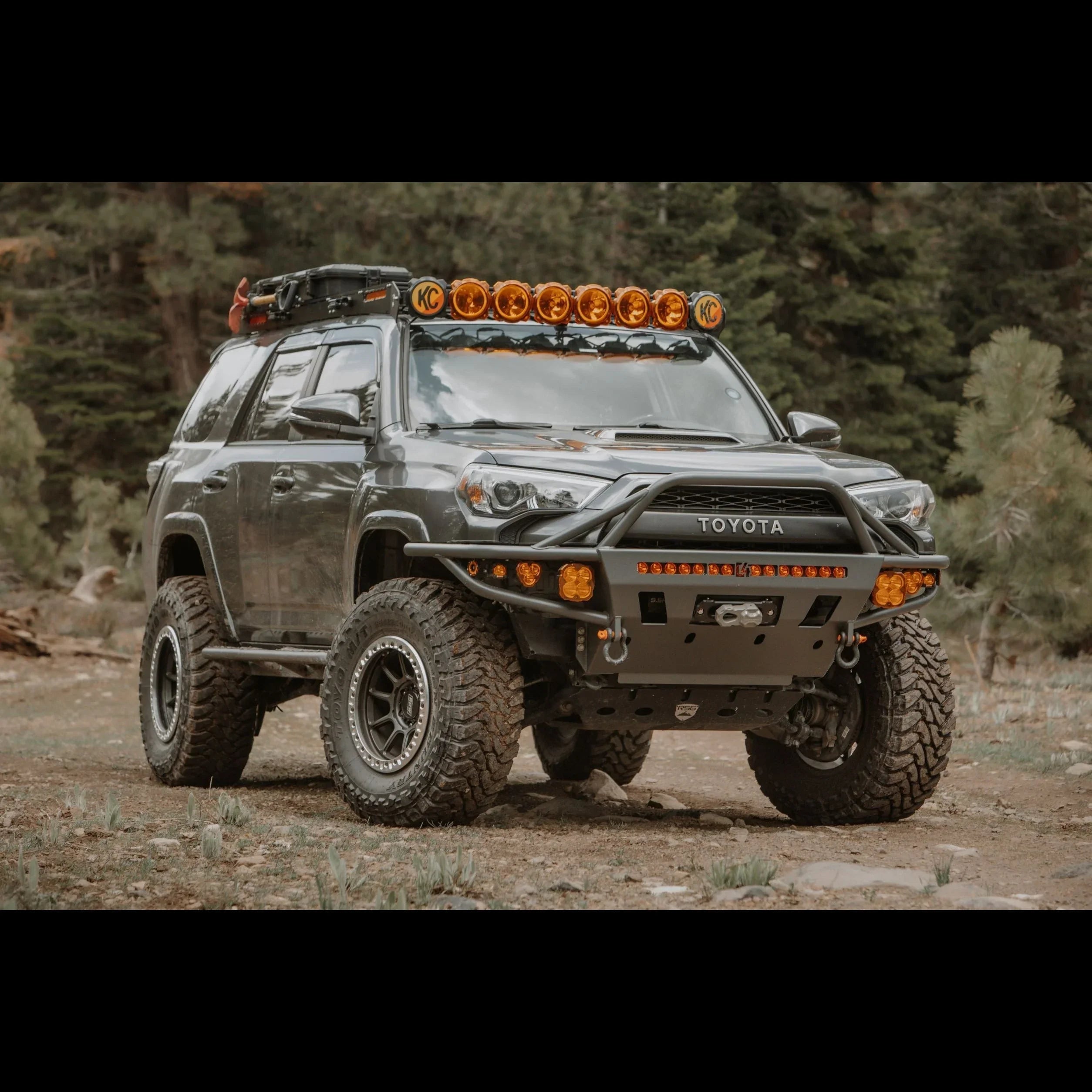 Toyota 4Runner off-road SUV with roof rack, KC lights, and rugged tires in a forest setting