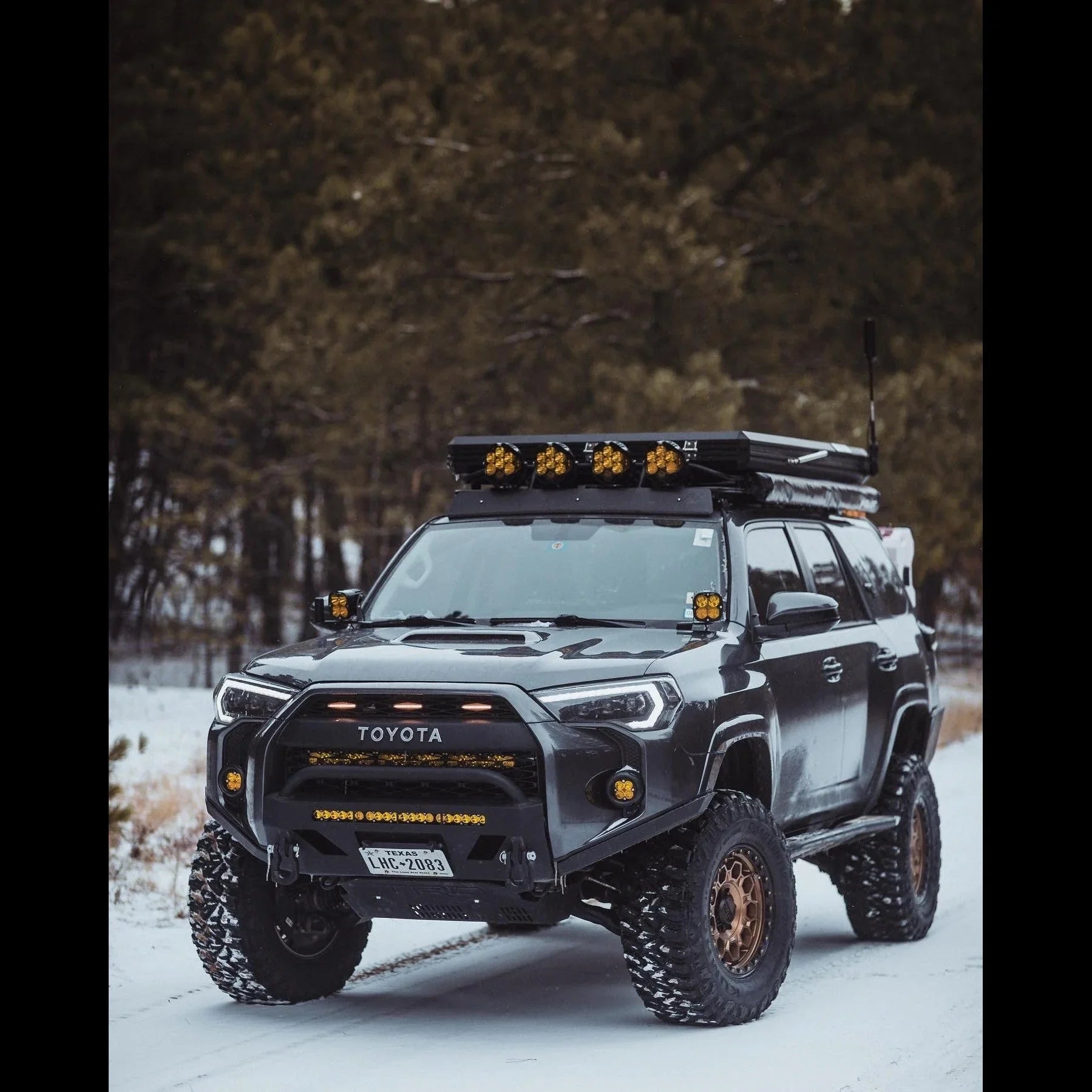 Toyota 4Runner overland SUV with off-road tires, roof rack, and LED lights on snowy trail