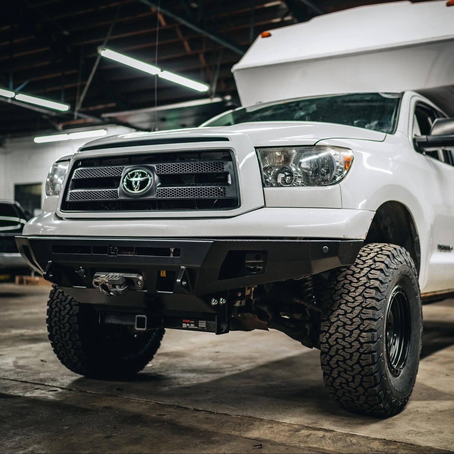 Toyota Tundra with off-road front bumper and winch in a garage setting
