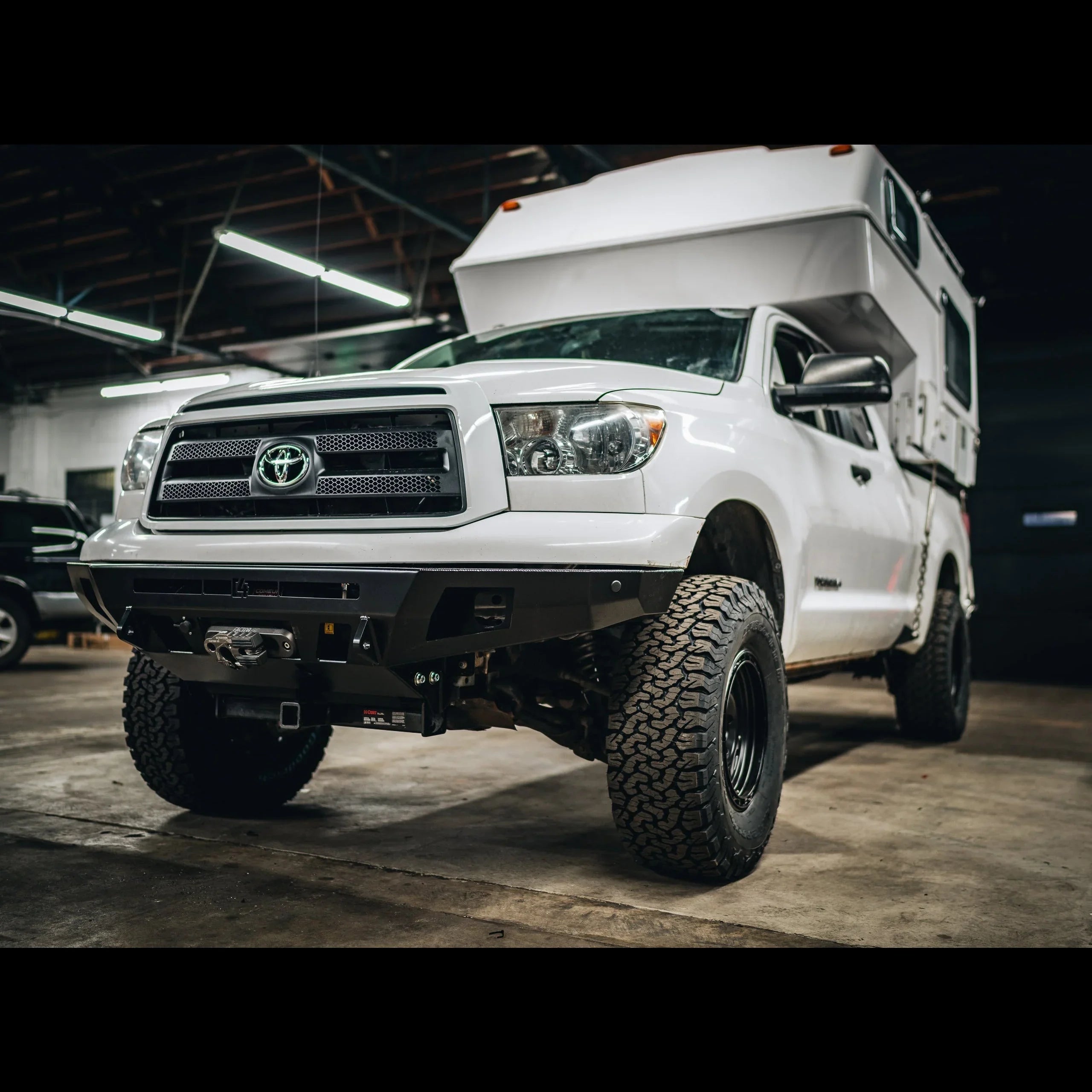 Toyota Tundra with off-road camper and rugged tires in indoor garage