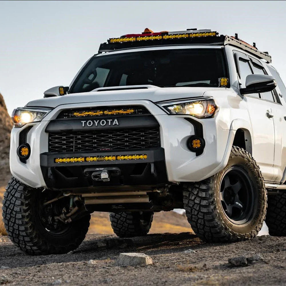 Lifted white Toyota 4Runner with off-road lights and accessories on rocky terrain