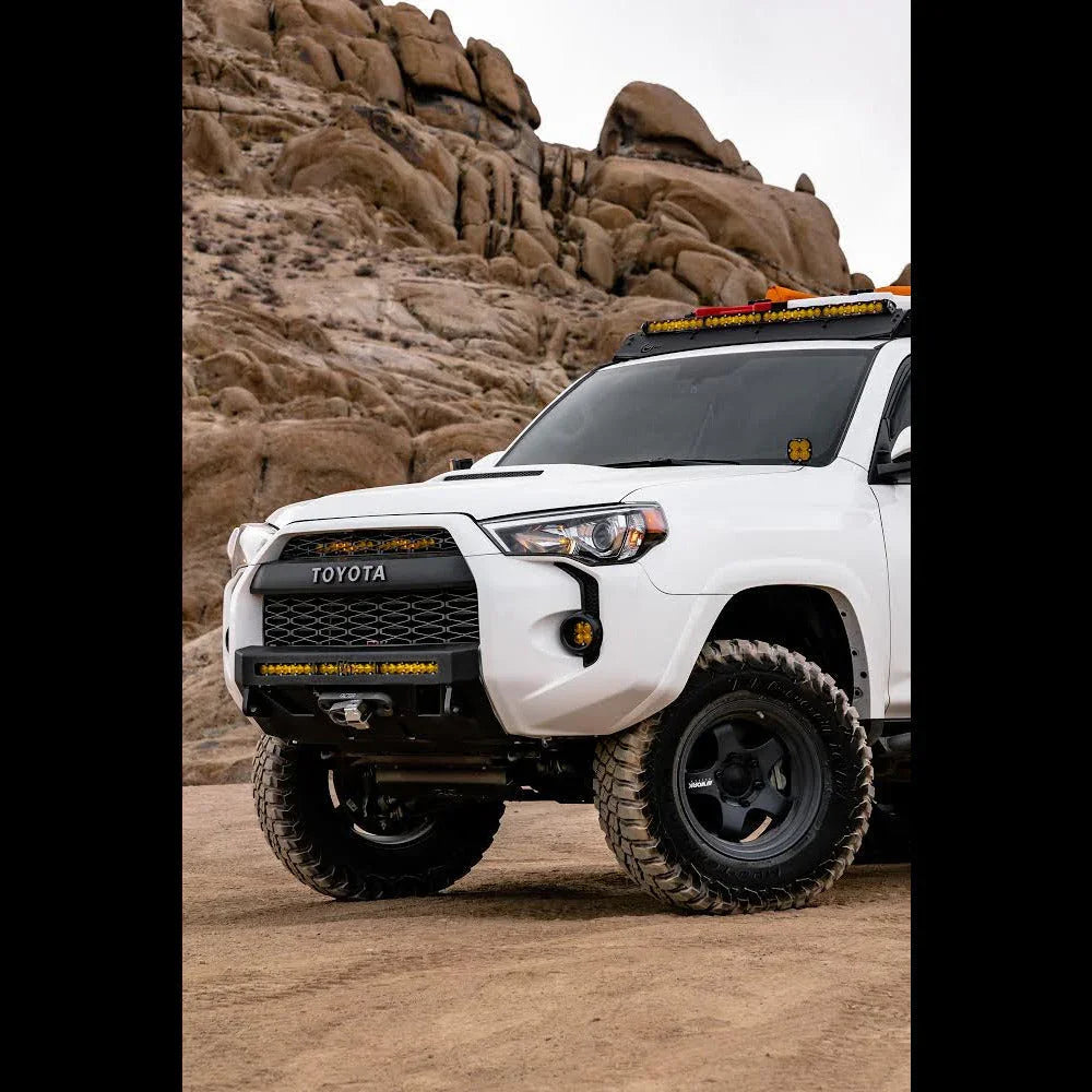 White Toyota 4Runner with off-road tires and LED lights parked in rocky desert terrain