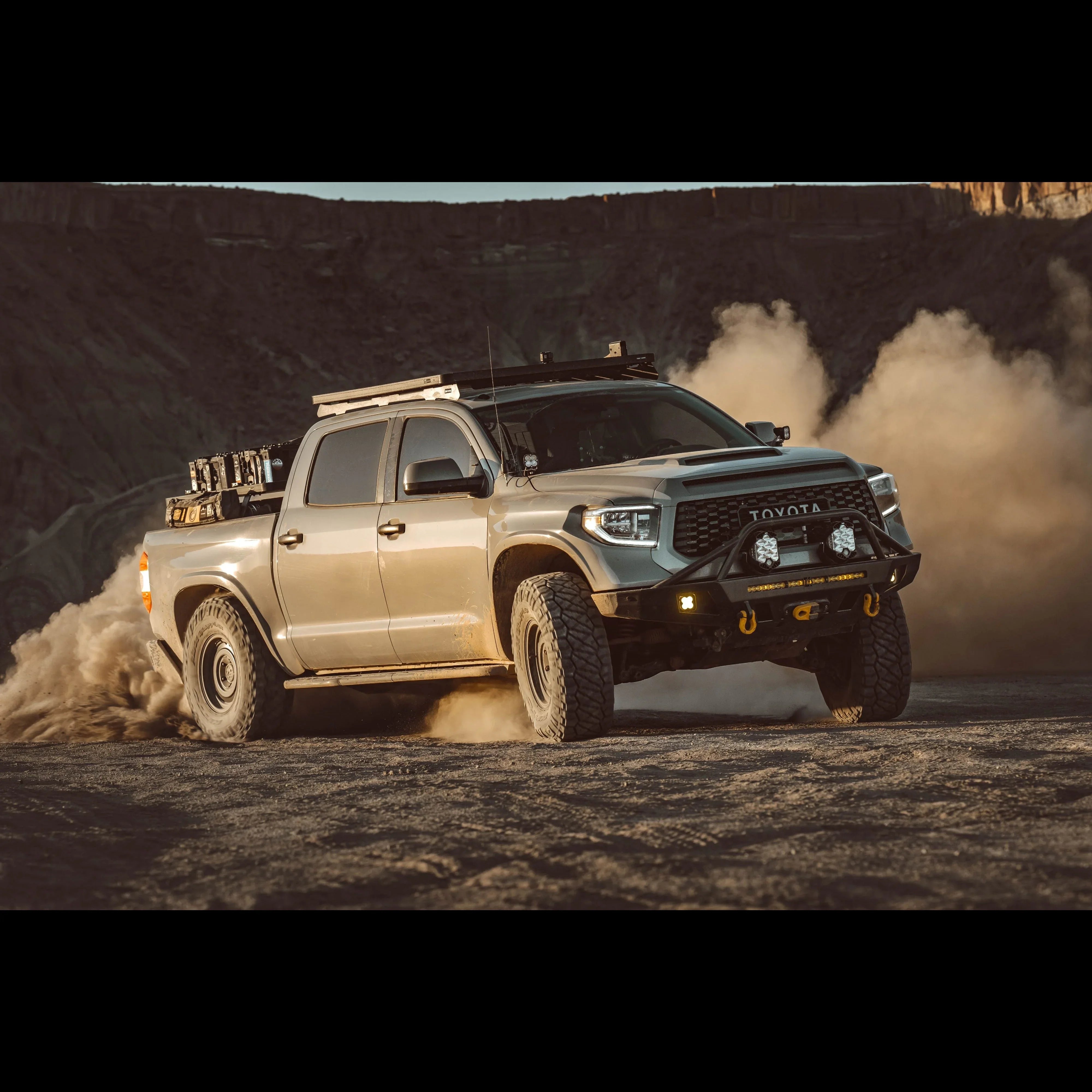 Lifted Toyota Tundra overlanding truck with roof rack and off-road gear driving on dirt