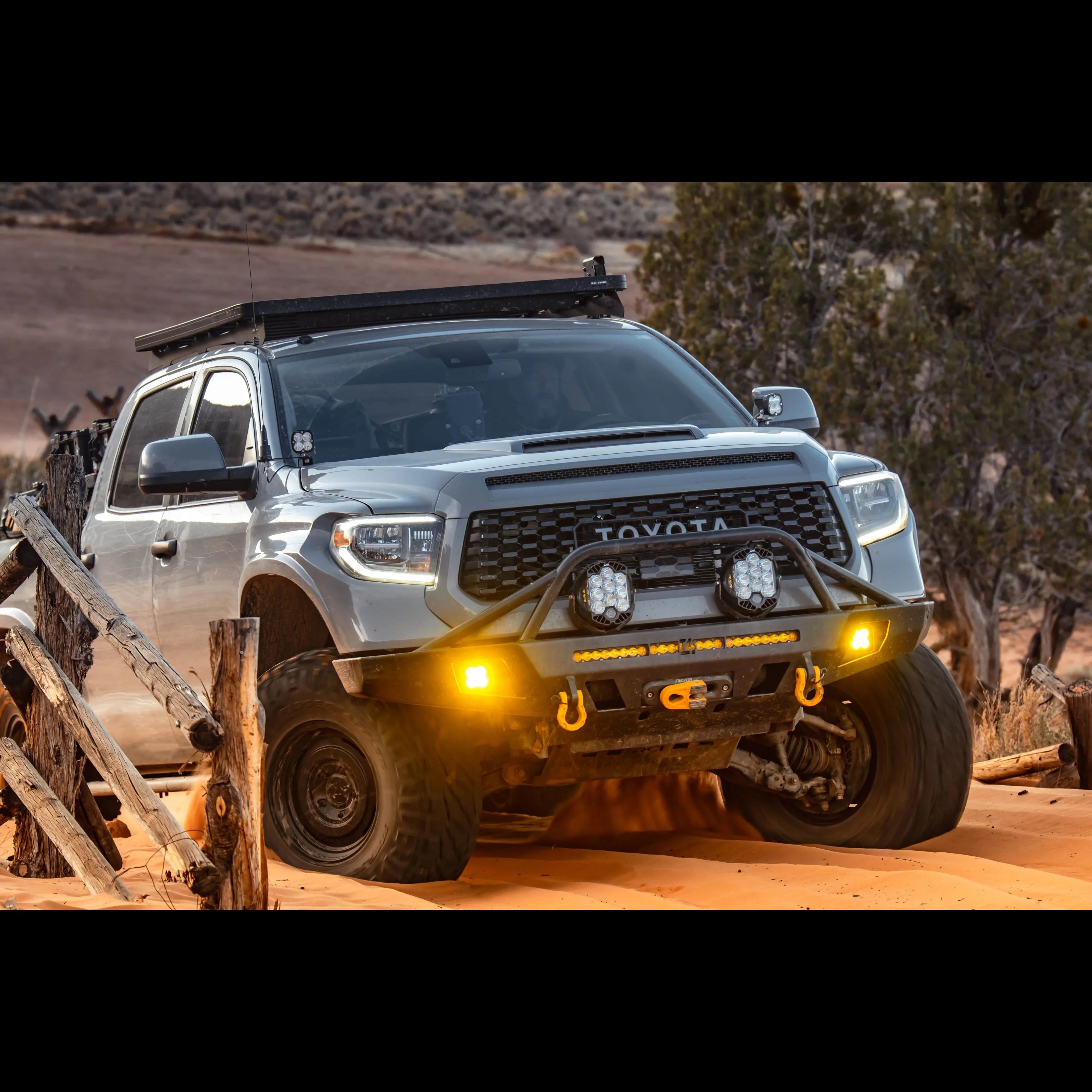 Toyota Tundra overlanding truck with off-road lights and roof rack driving on desert trail