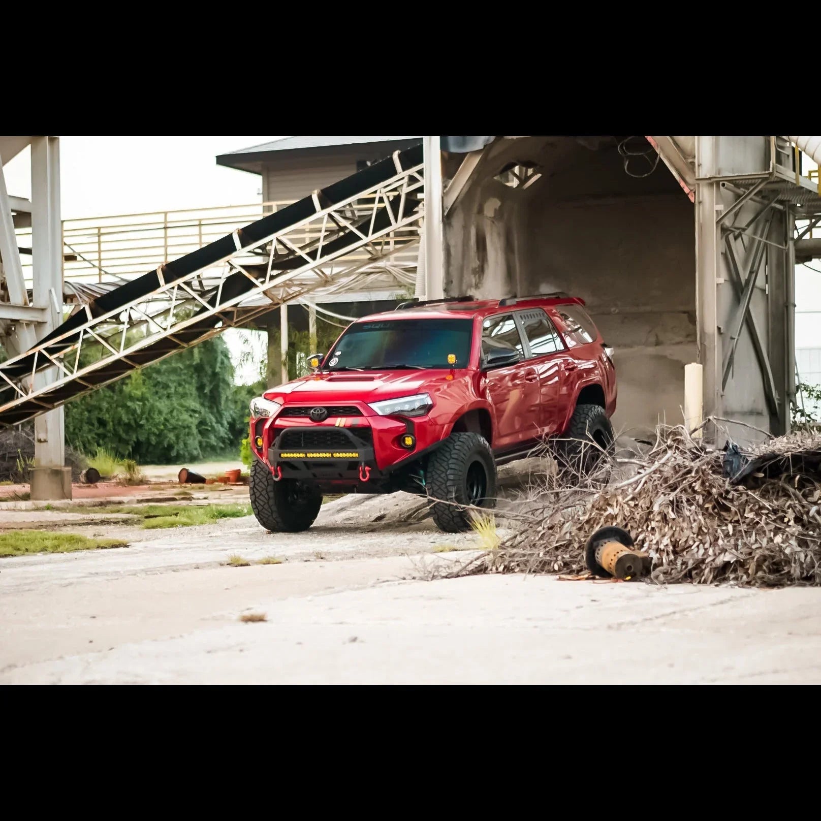 Red Toyota 4Runner overland SUV with off-road accessories at industrial outdoor site