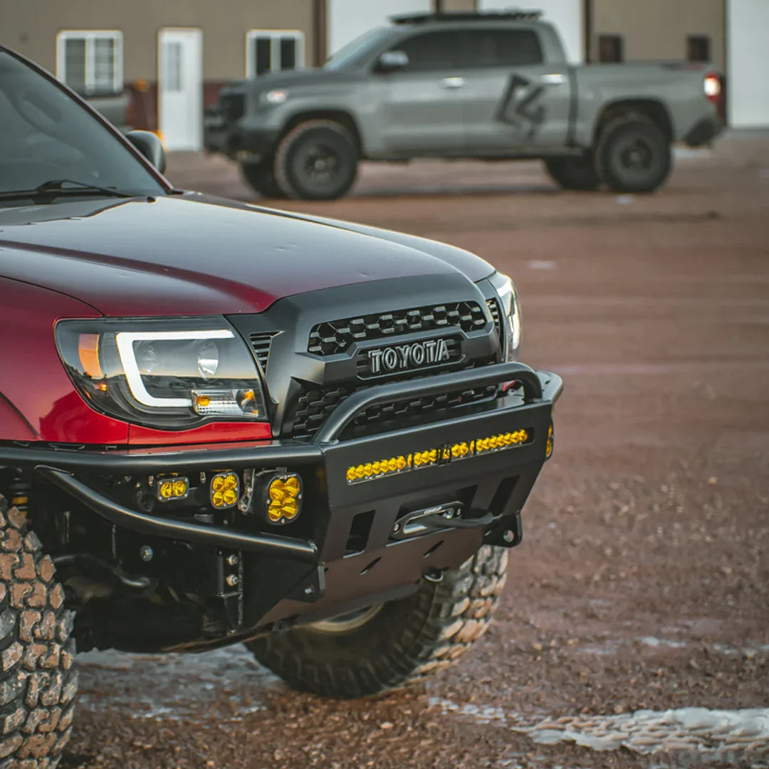 Toyota Tacoma with heavy-duty front bumper and off-road lights on dirt lot