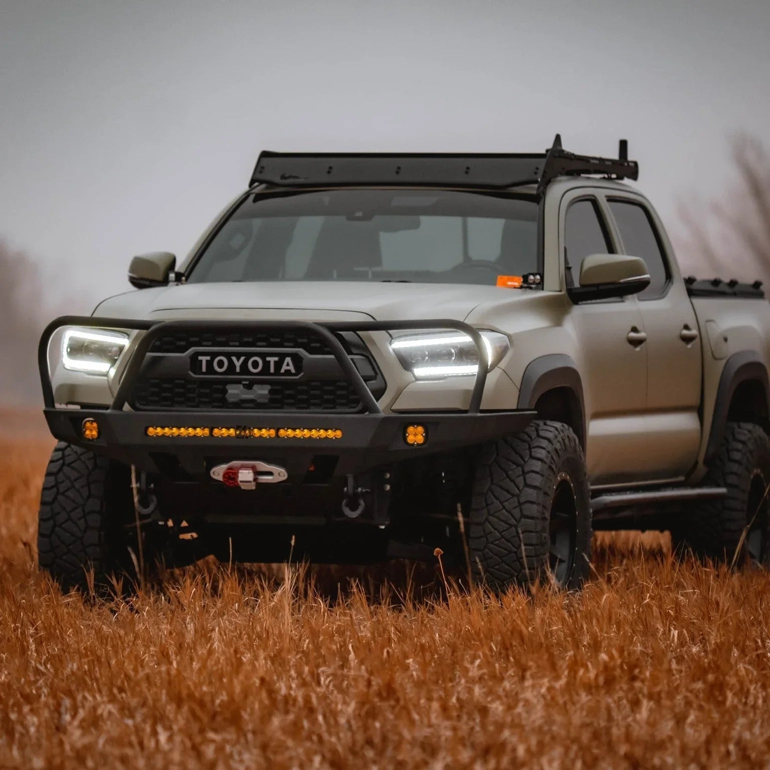 Front view of a 3rd gen Toyota Tacoma with overland front bumper, off-road lights, and rugged tires.