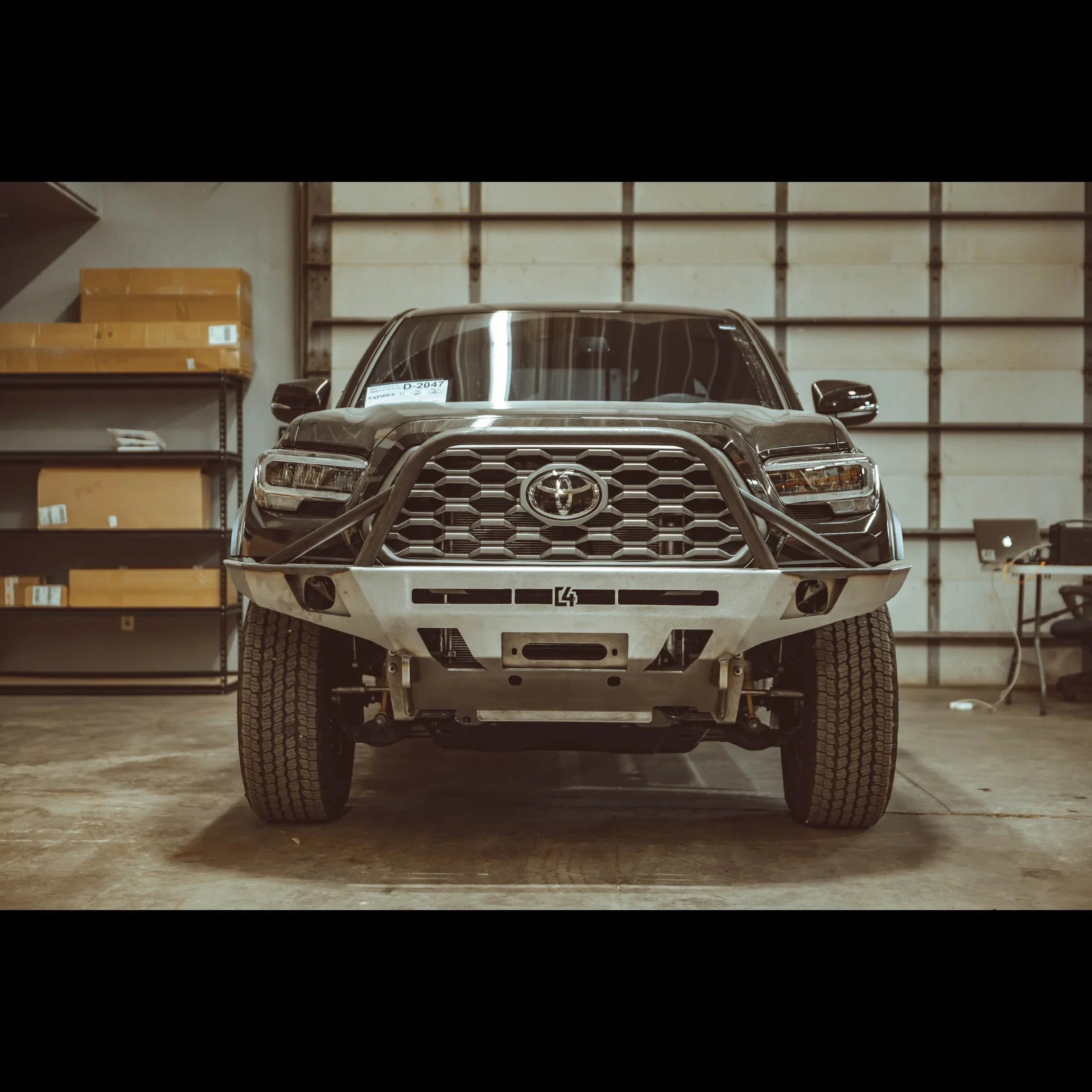 Toyota Tacoma with overland front bumper, 3rd gen, in a garage workshop