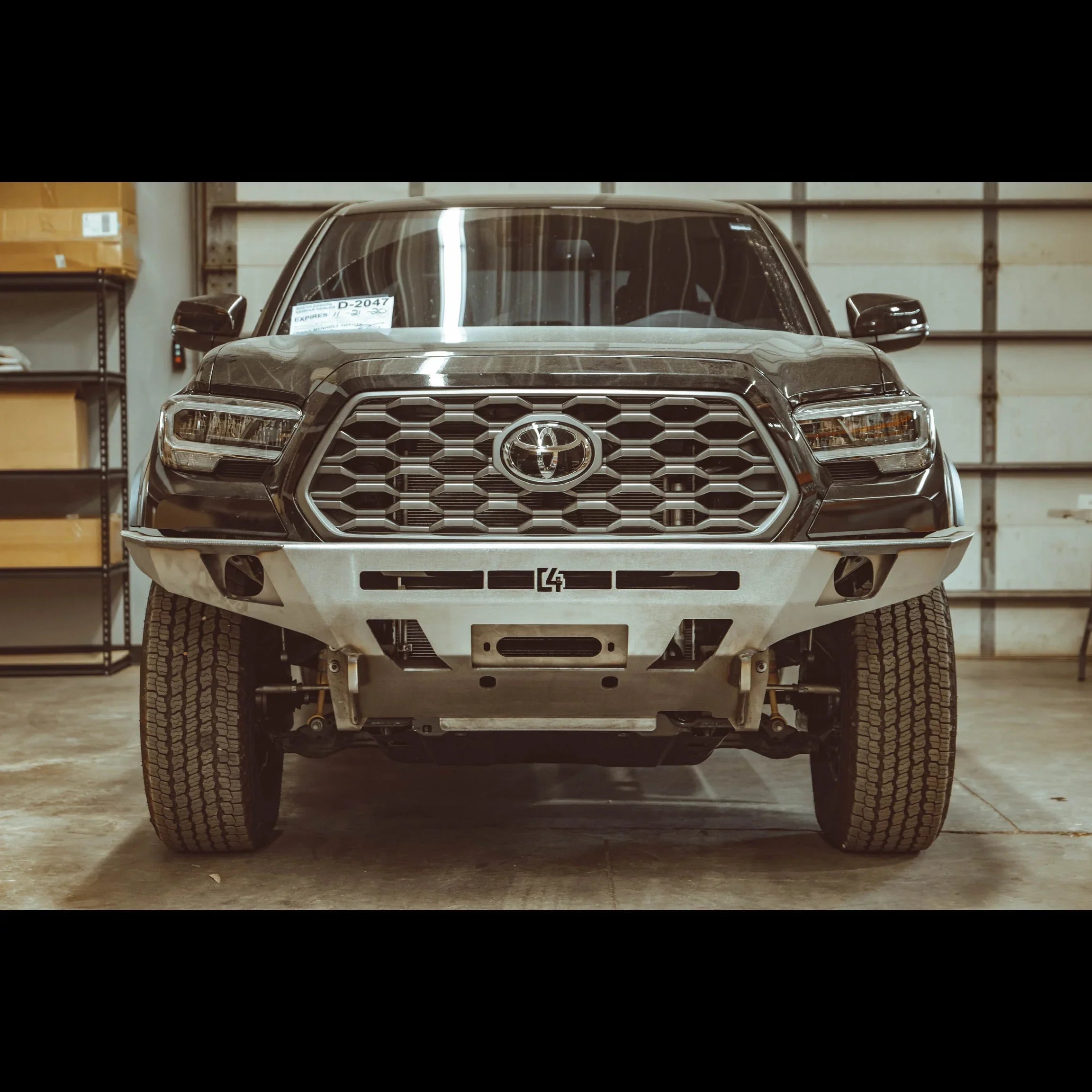 Front view of Toyota Tacoma 3rd gen with custom overland steel bumper in garage