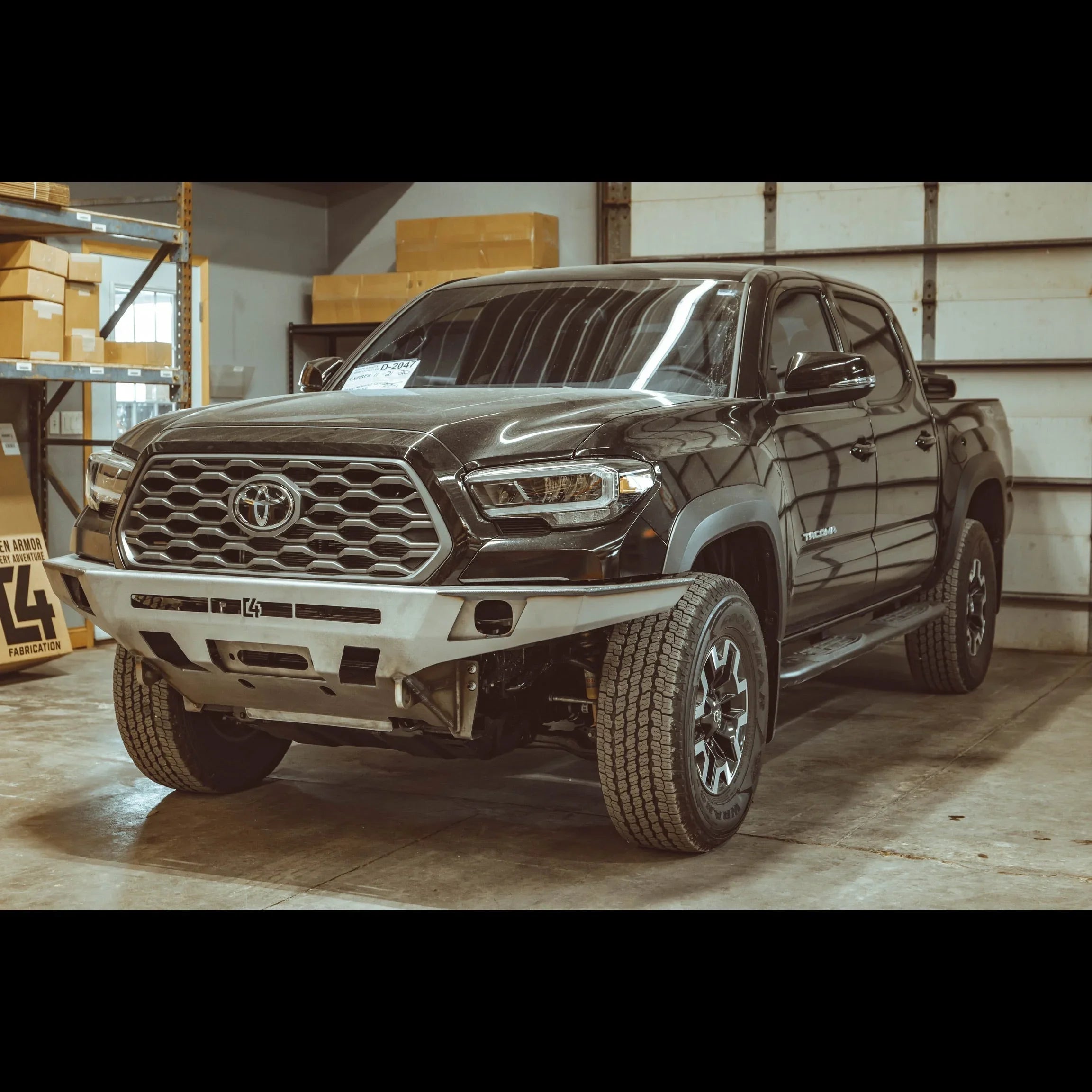 2016-2023 Toyota Tacoma with aftermarket overland front bumper in a garage