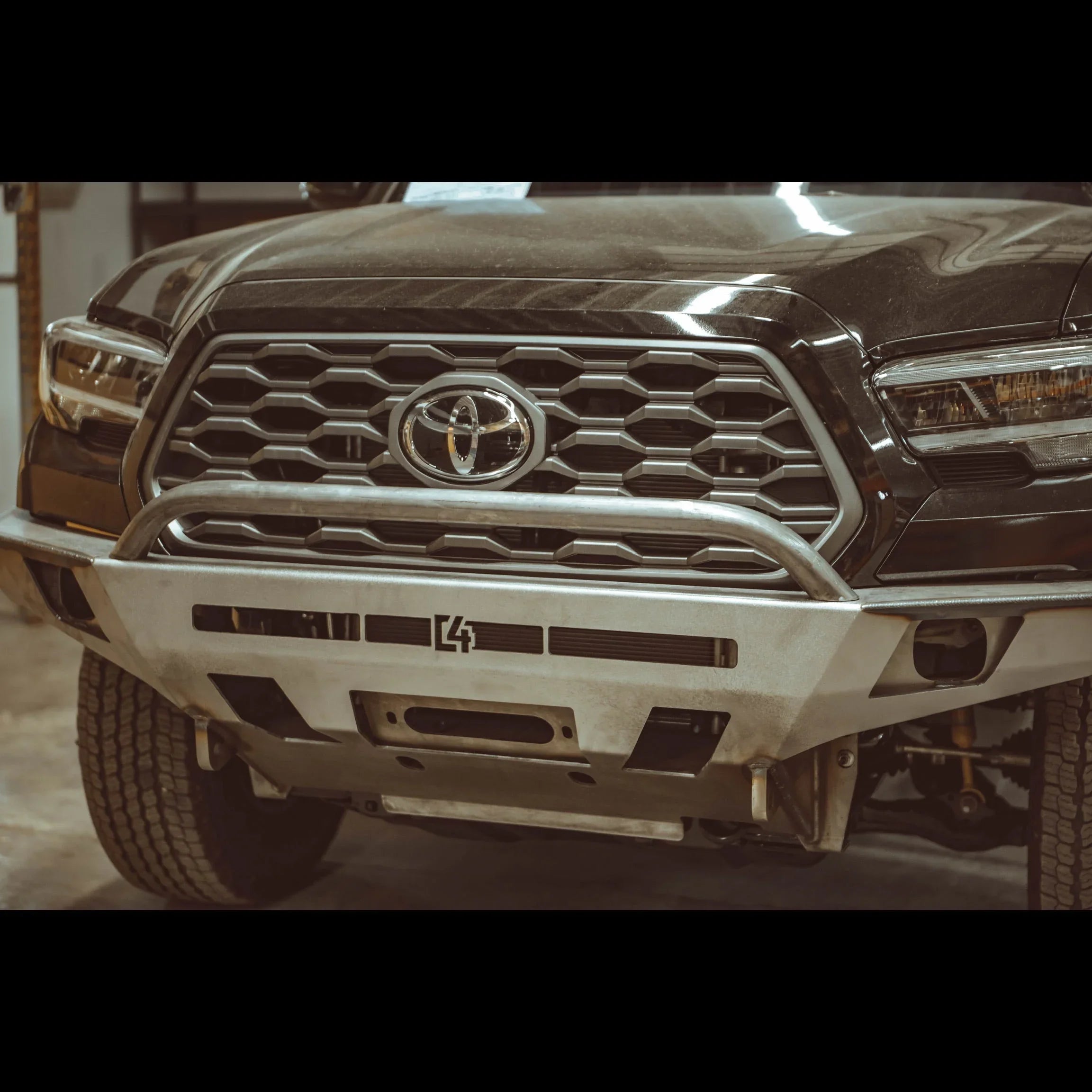 Toyota Tacoma 3rd gen overland front bumper with bull bar and skid plate in garage