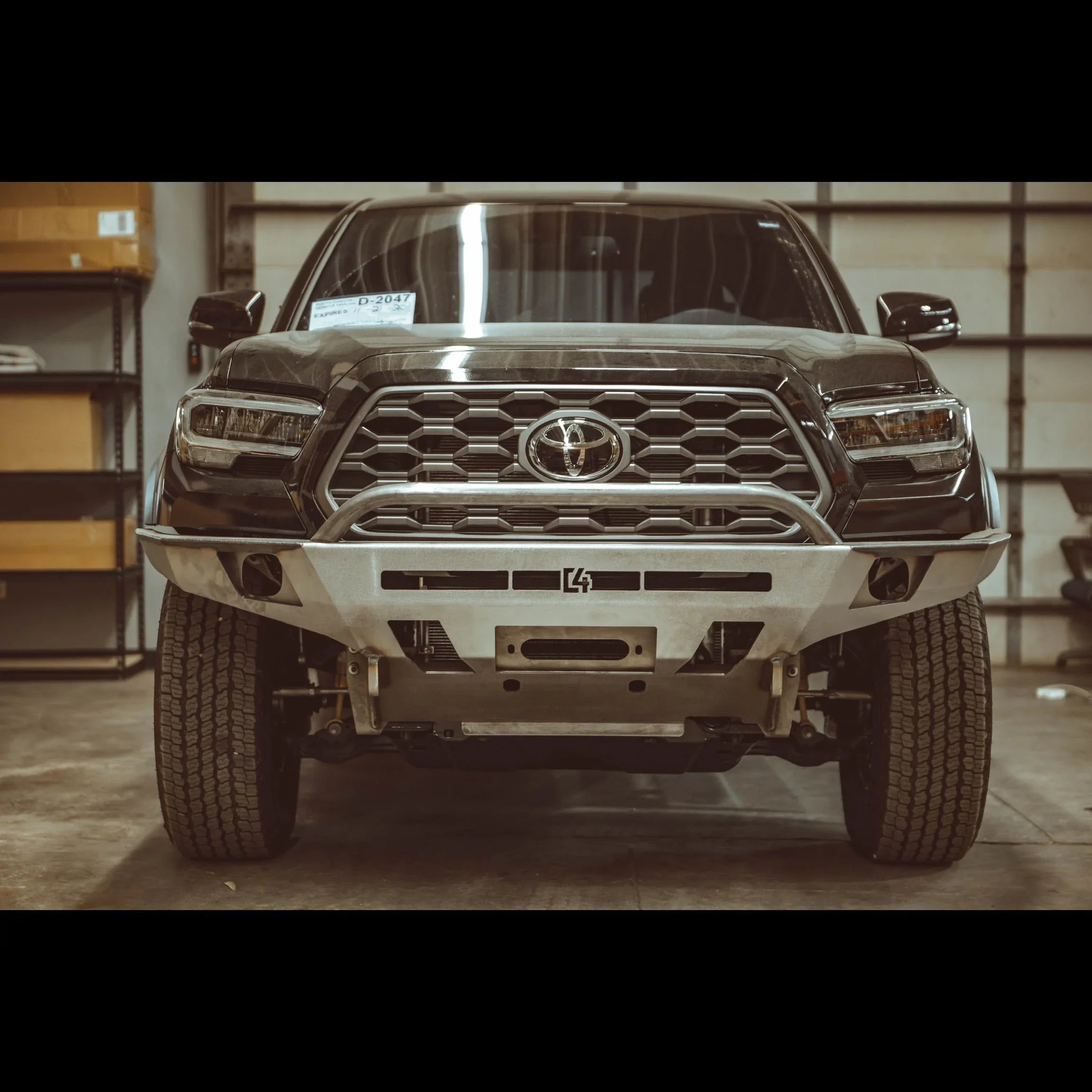 Toyota Tacoma 3rd Gen with overland front bumper, off-road ready, parked in a garage