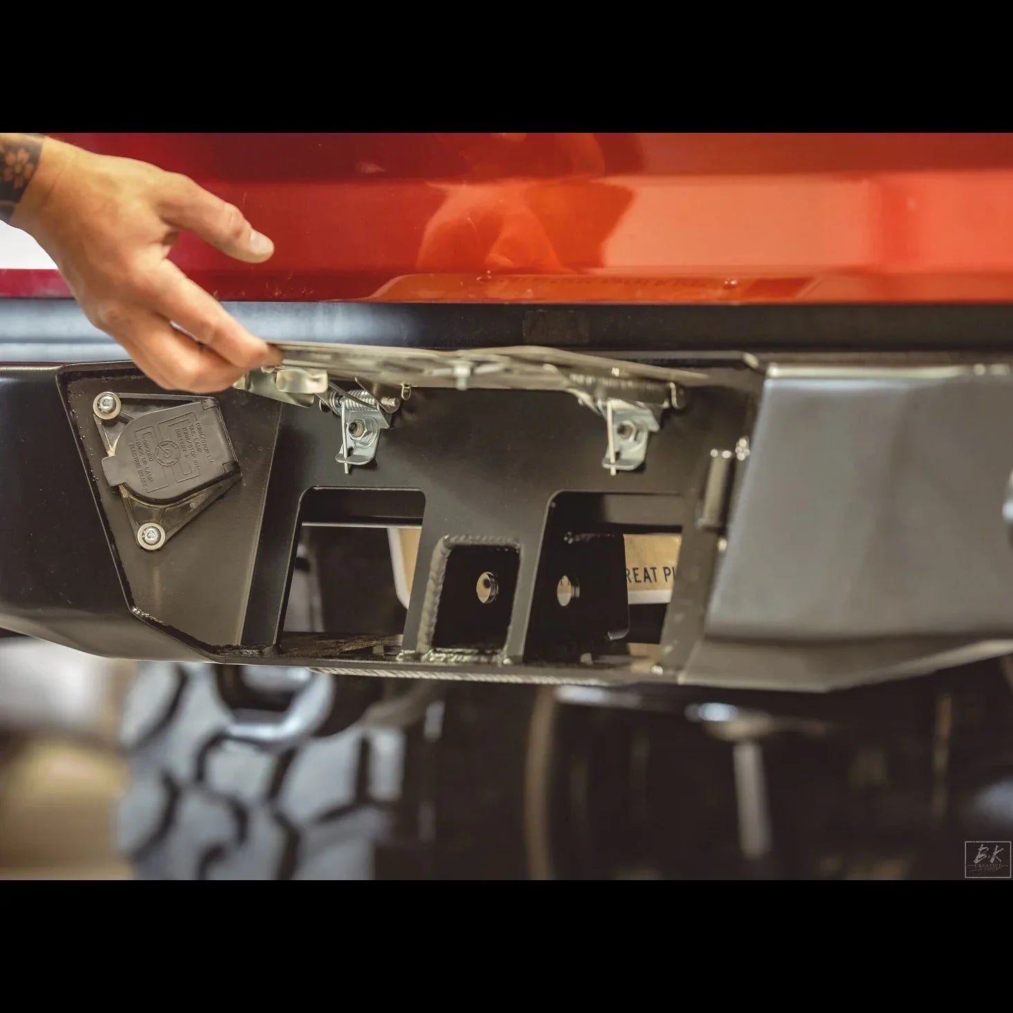 Hand installing steel rear bumper with license plate bracket on Toyota Tacoma