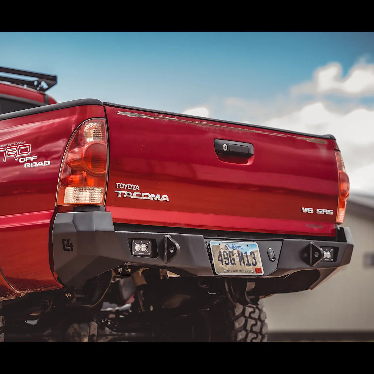 Aftermarket rear bumper installed on red Toyota Tacoma truck for off-road overlanding