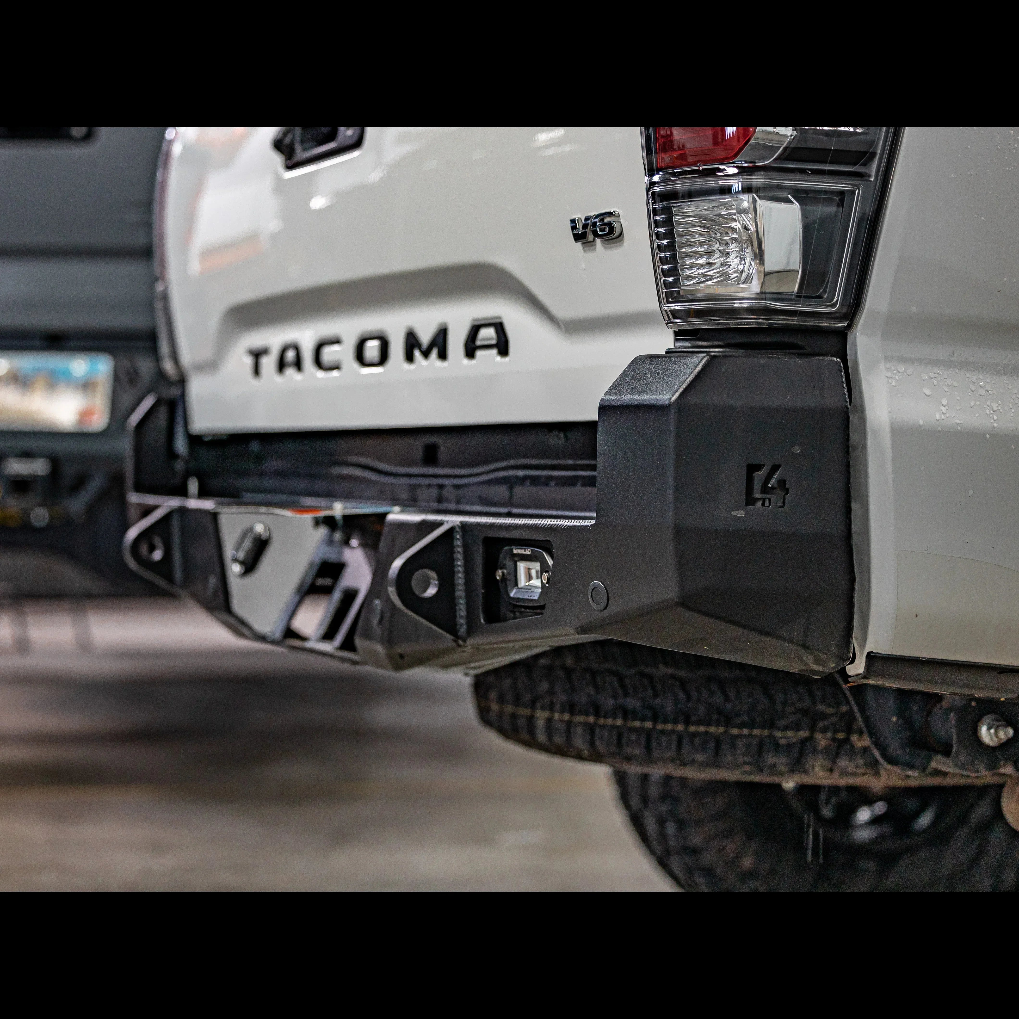 Overland rear bumper installed on white Toyota Tacoma 3rd Gen, close-up view