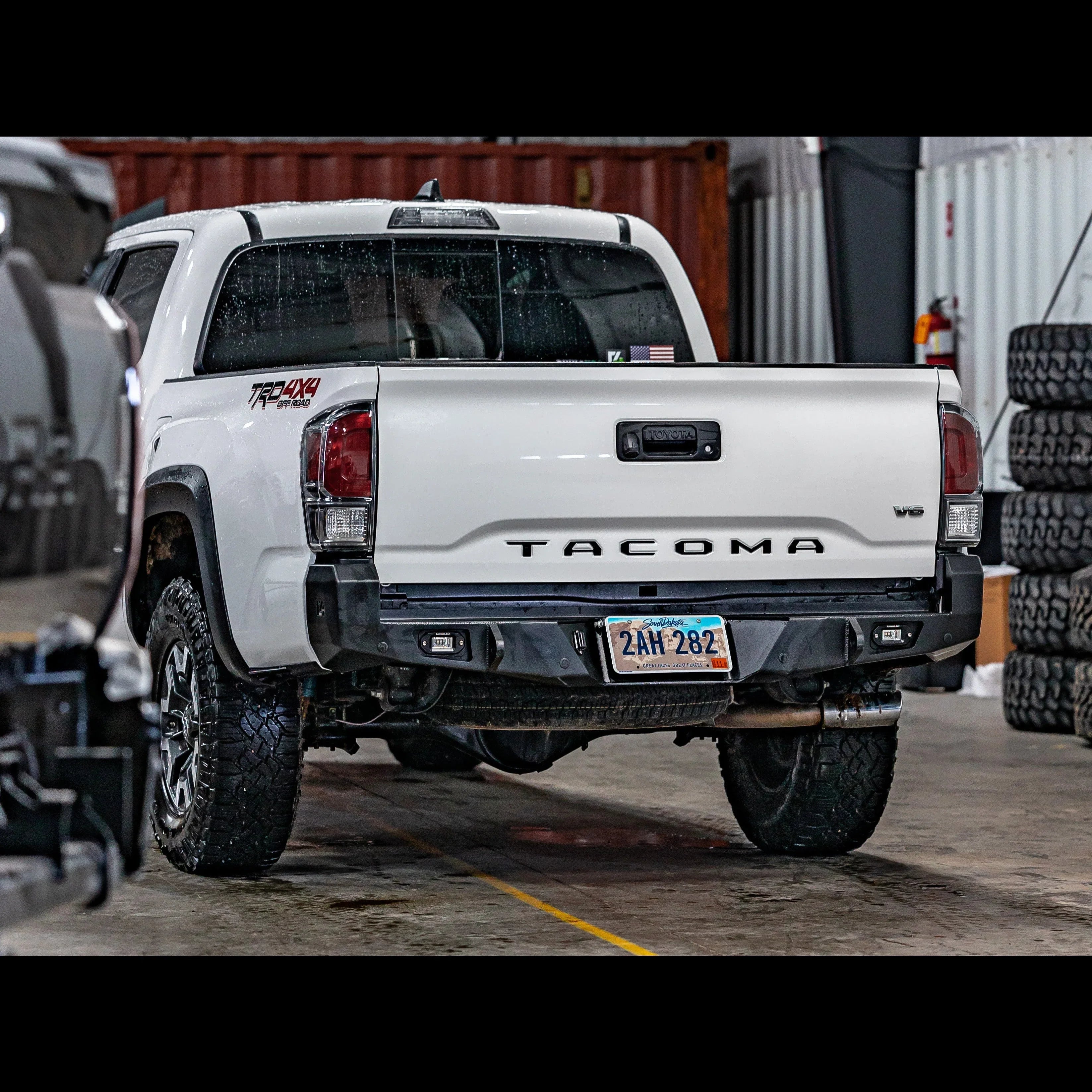Toyota Tacoma 3rd Gen with overland rear bumper, off-road tires, in garage setting