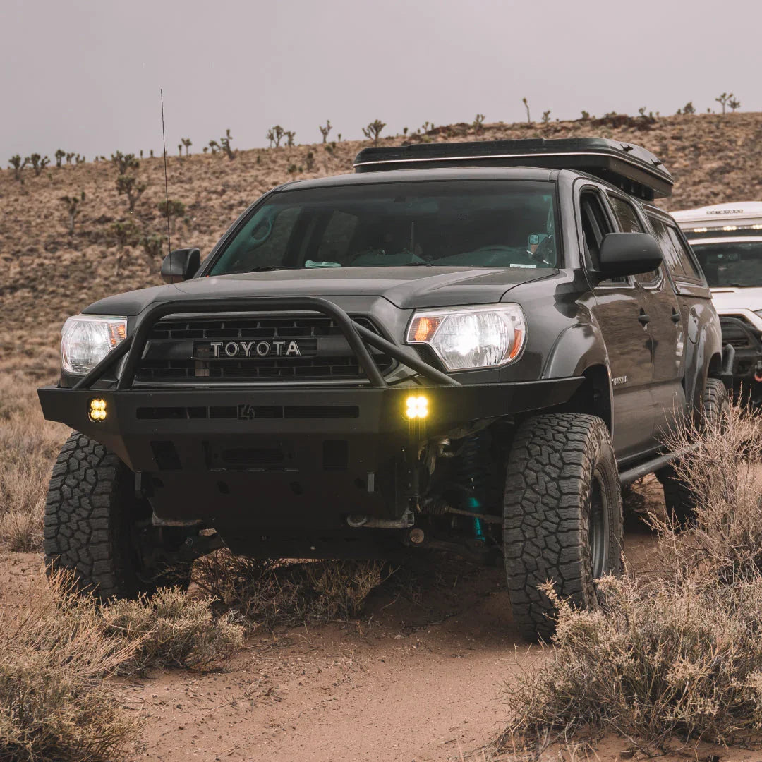 Toyota Tacoma with overland front bumper and off-road lights in desert landscape