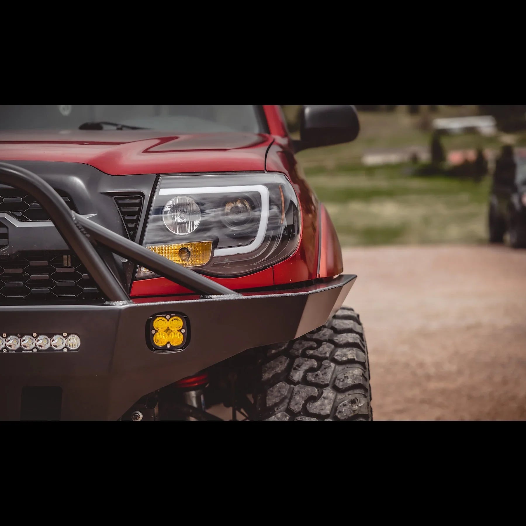 Toyota Tacoma overland front bumper with off-road lights and rugged tire, outdoor setting