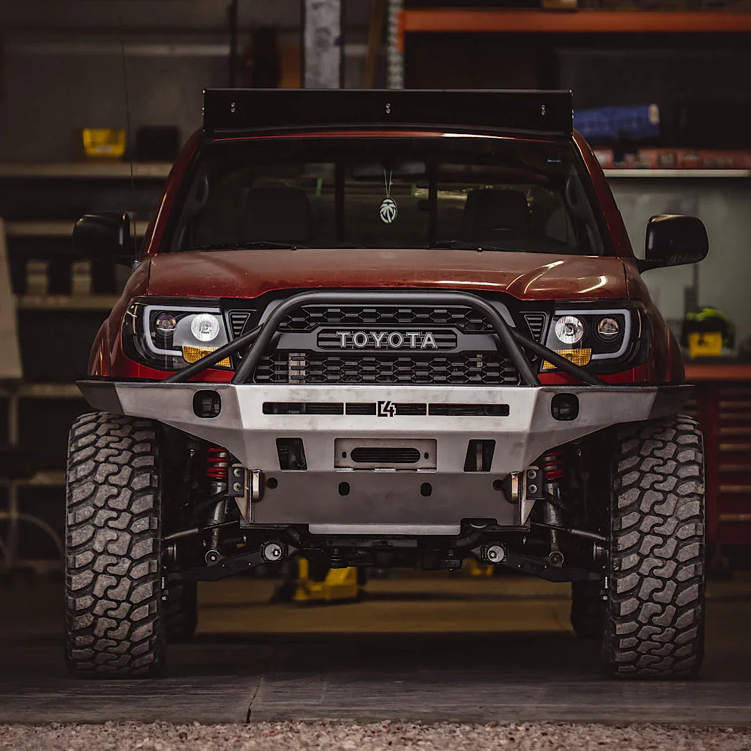 Front view of Toyota Tacoma with overland steel off-road bumper and all-terrain tires in garage