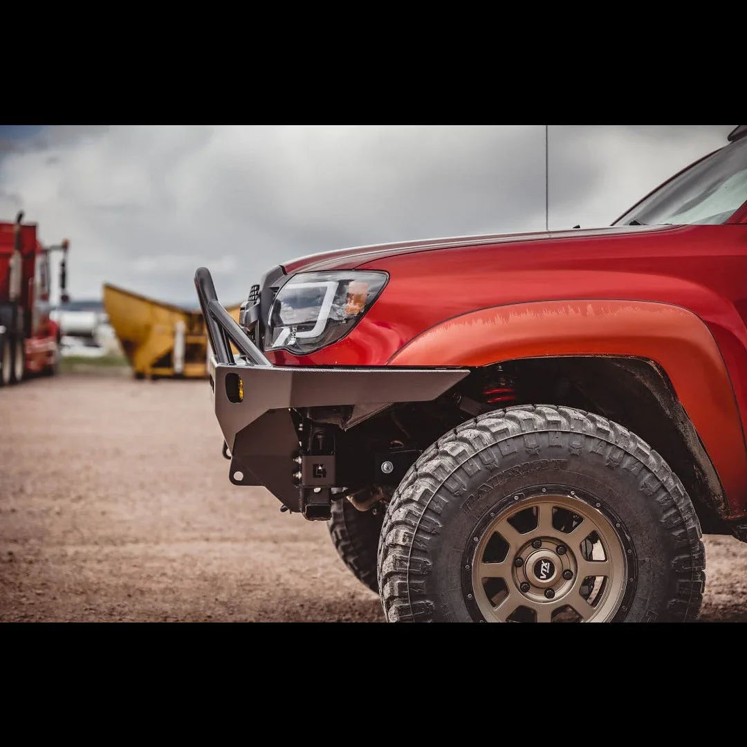 Front view of red Toyota Tacoma with overland front bumper and off-road tires
