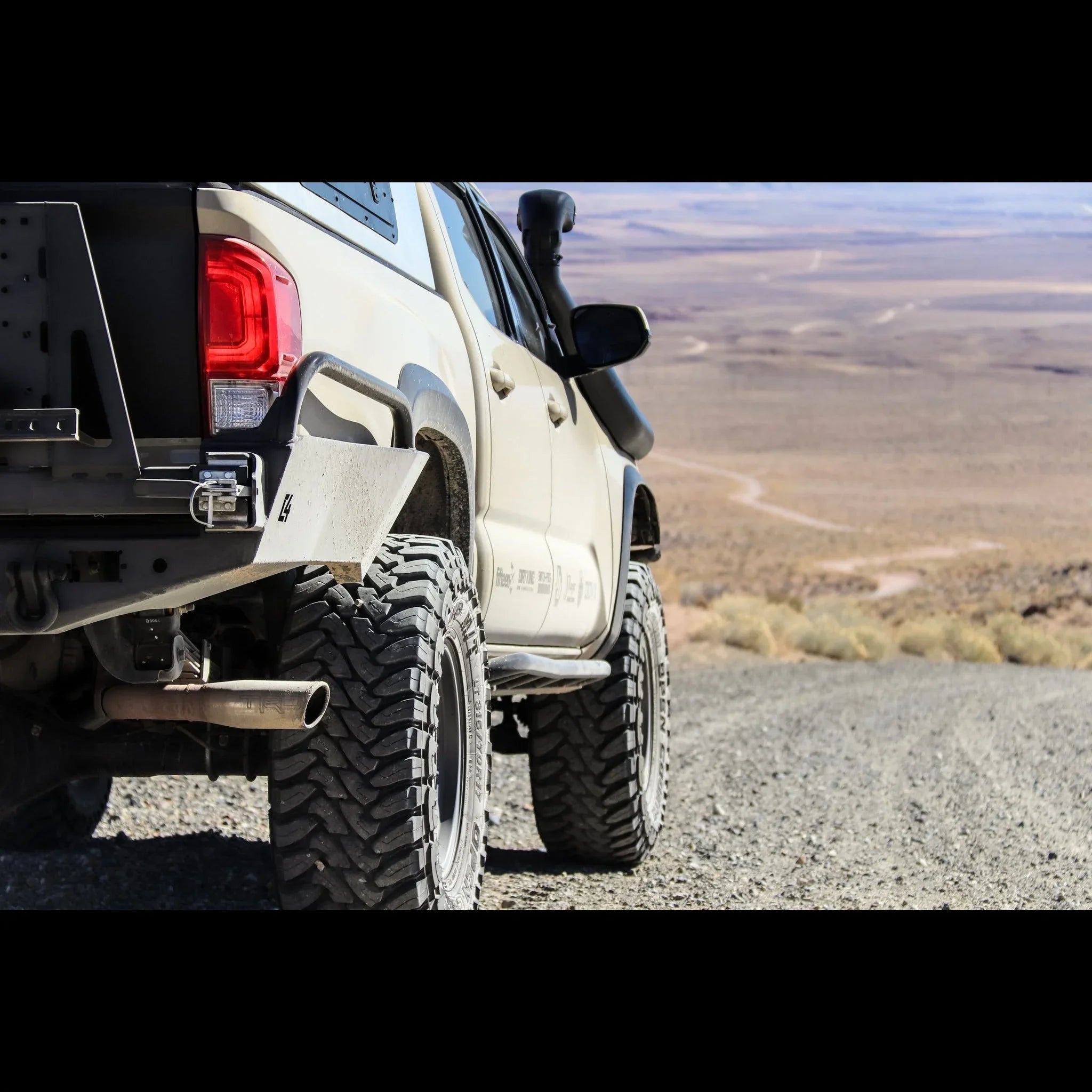 Toyota Tacoma with high clearance rear bumper and off-road tires on a desert trail