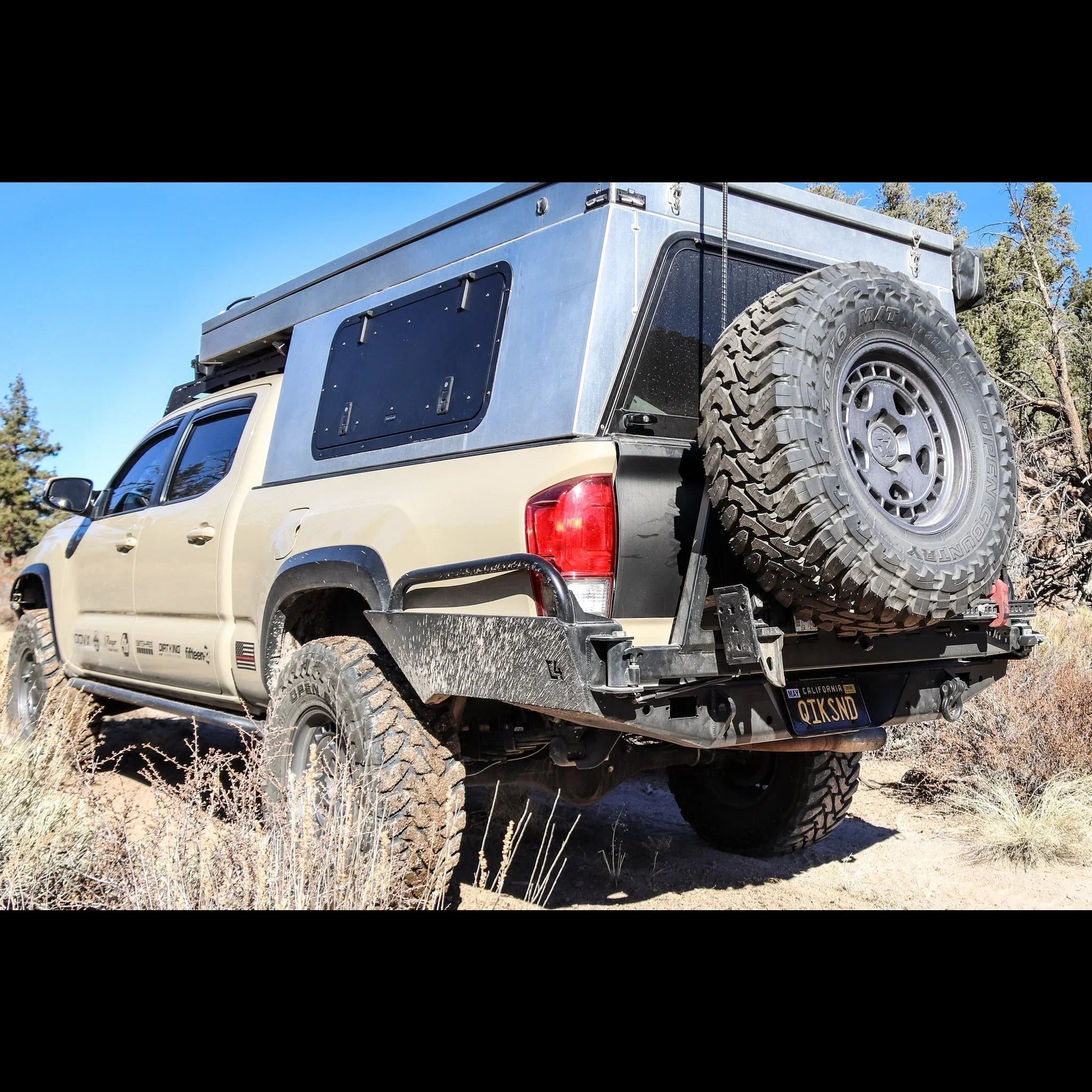 Toyota Tacoma with high clearance overland rear bumper and spare tire mount on rugged trail