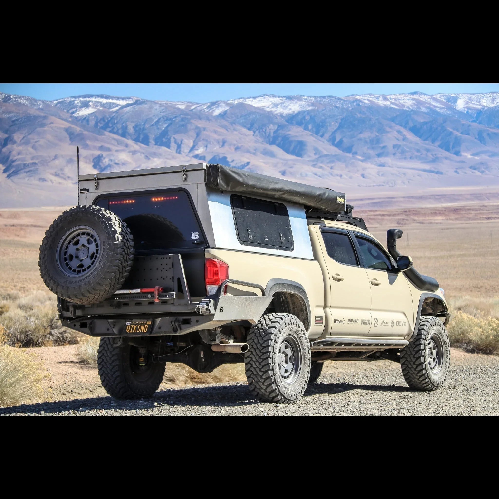 Toyota Tacoma with high clearance rear bumper, spare tire, overland gear in desert landscape