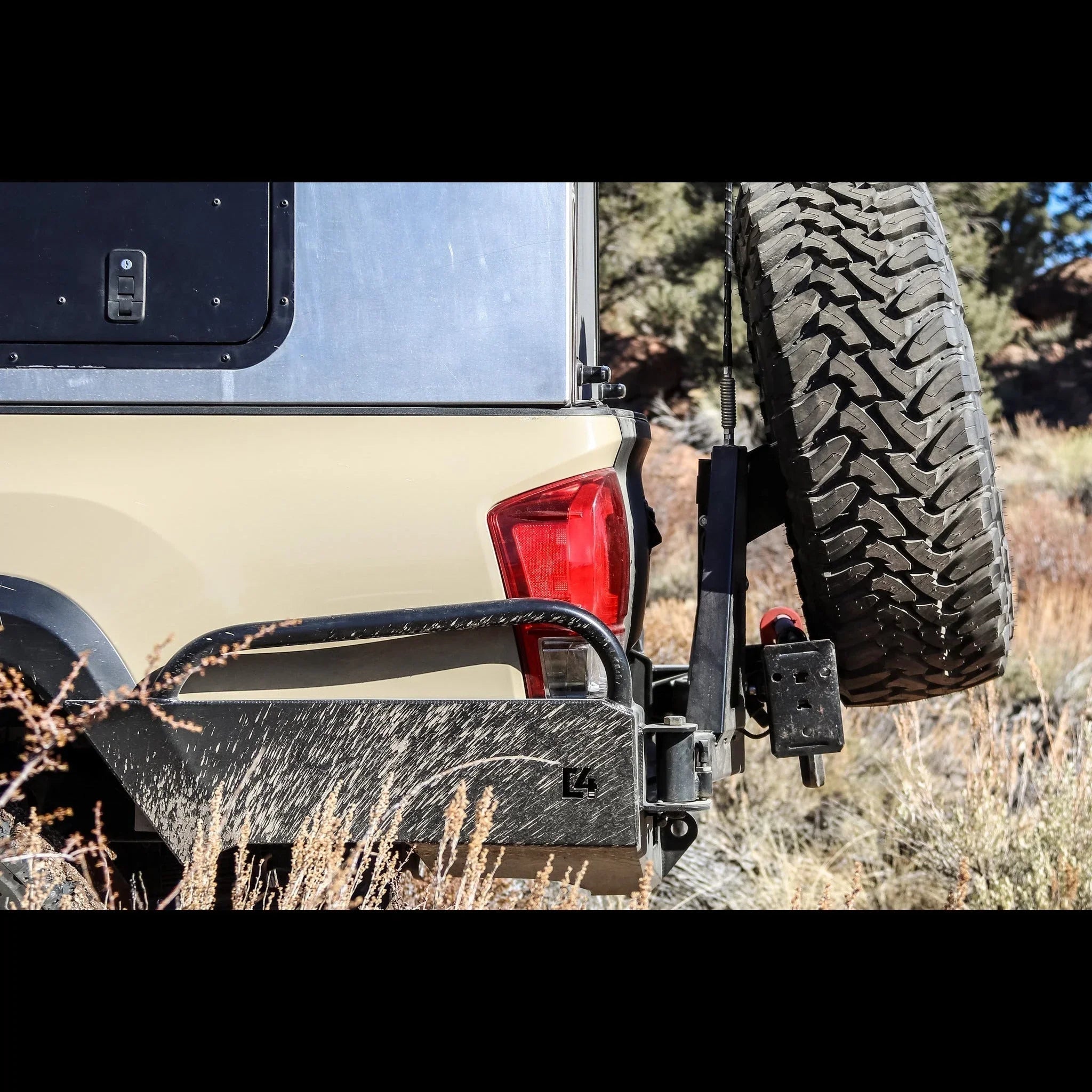 Toyota Tacoma rear bumper with high clearance and mounted spare tire in outdoor setting