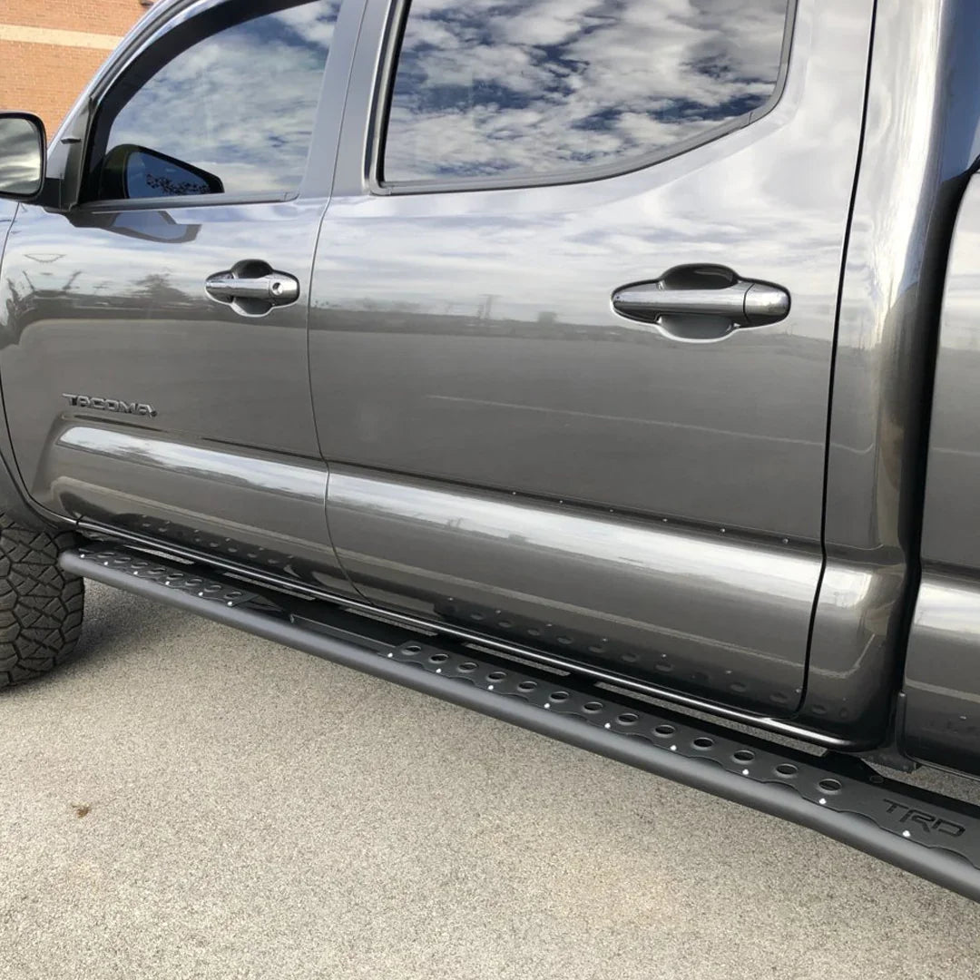 Black rock sliders installed on a Toyota Tacoma pickup truck for off-road protection