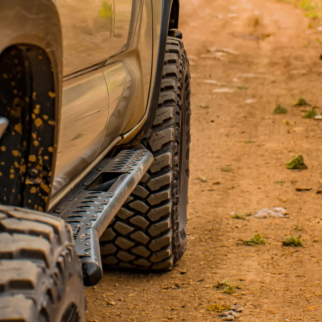 Toyota Tacoma with rock sliders and off-road tires on a dirt trail