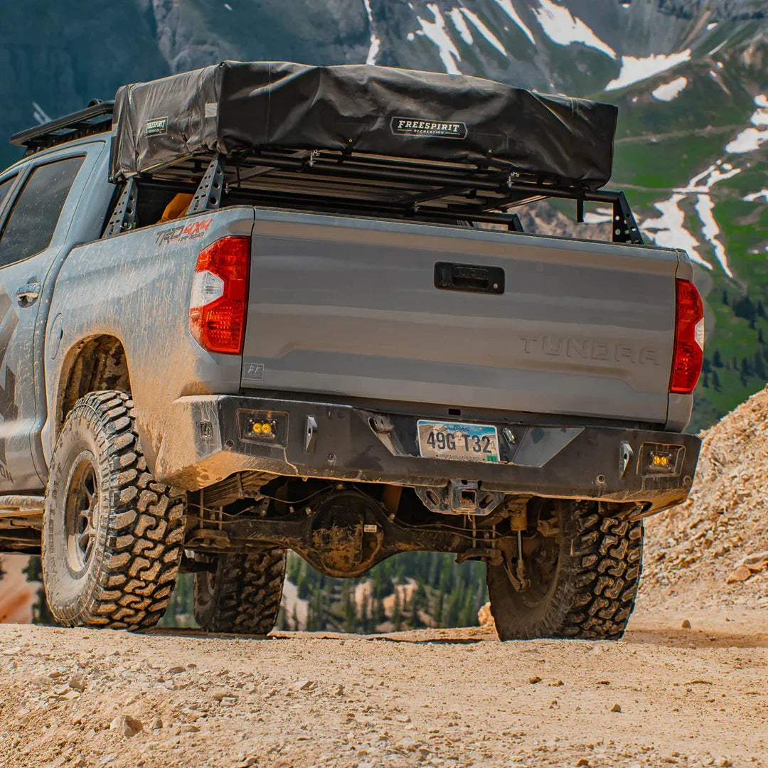 Toyota Tundra with overland rear bumper and off-road gear on a rugged mountain trail