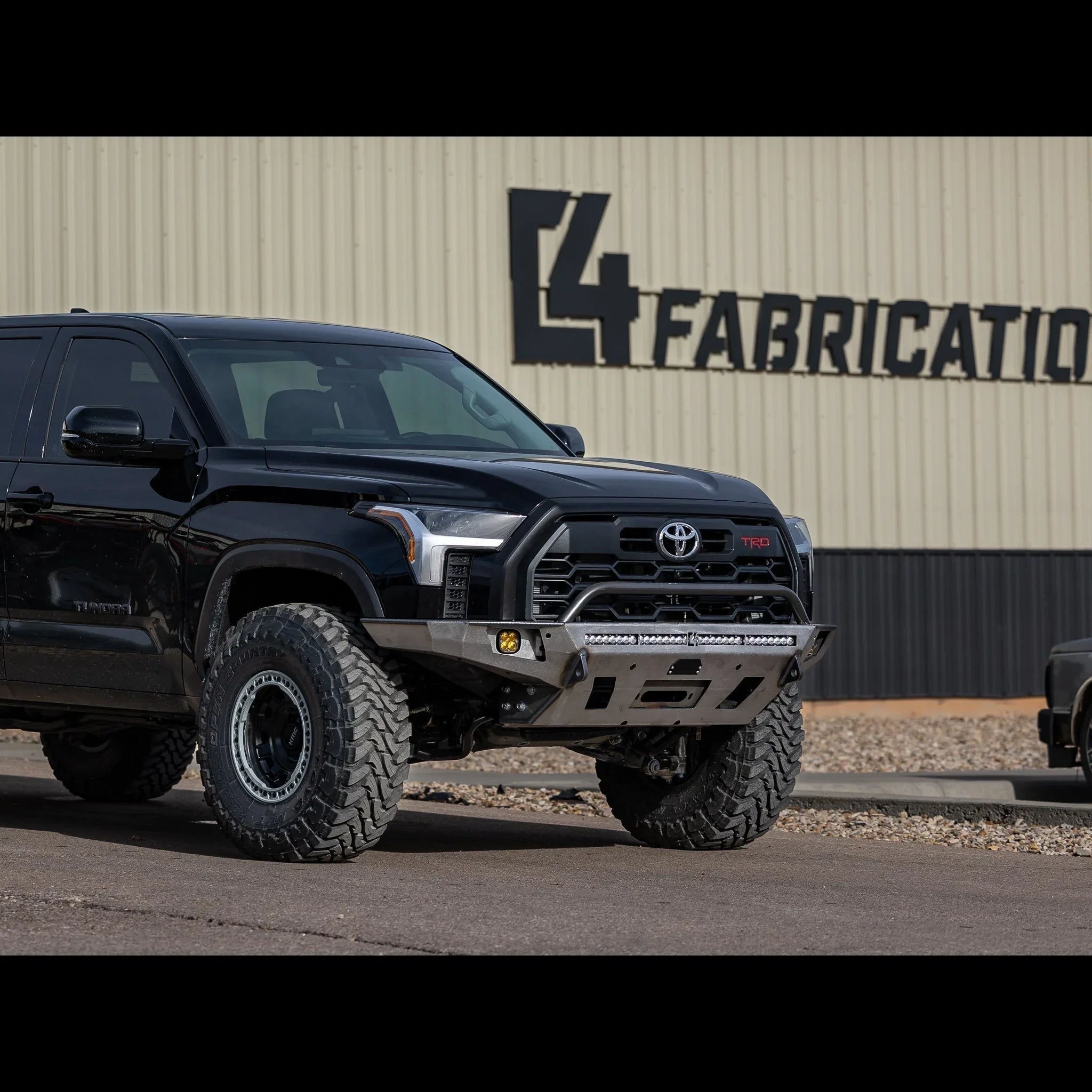 Toyota Tundra 2022 with overland front bumper and off-road tires in industrial setting